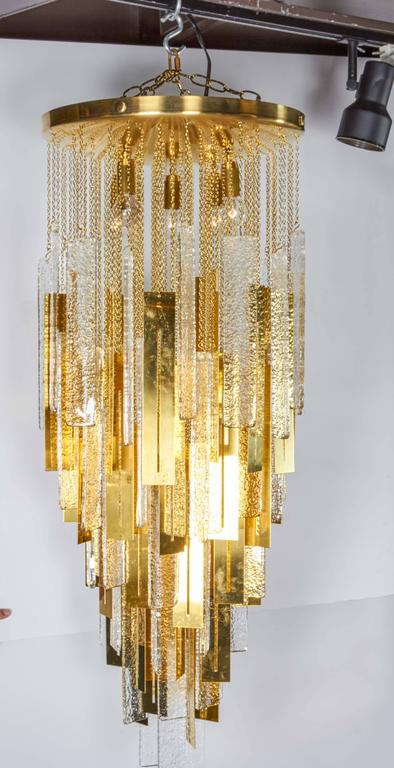 Spectacular large-scale chandelier comprised of alternating Murano glass and brass metal pendants, each hanging from their individual chain. The glass components are hand blown with flat rectangular design and with textured details. The chandelier