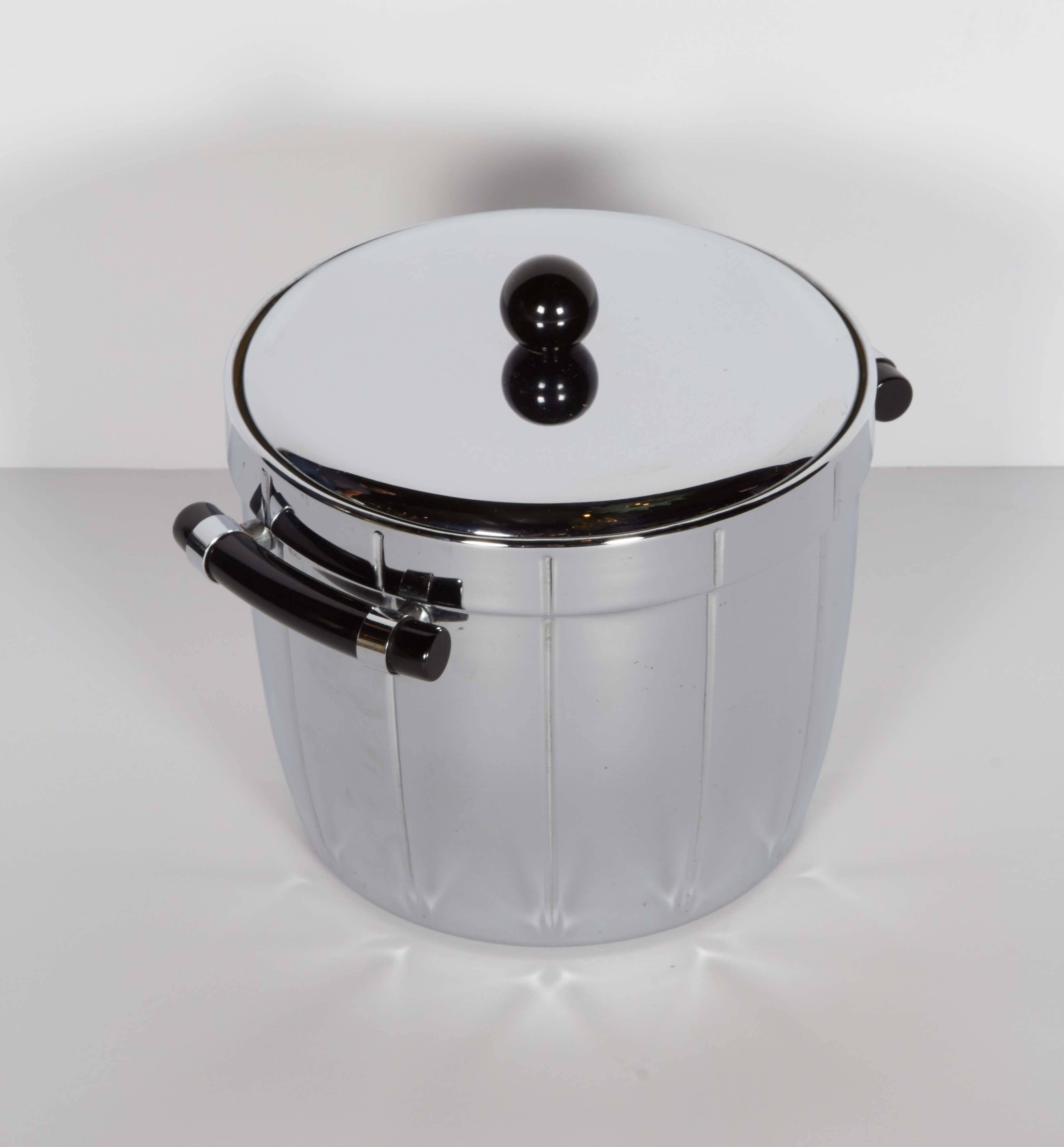 Art Deco ice bucket with handsome Machine Age design. The ice bucket is made of highly polished chrome and features exquisite black bakelite handles and top finial detail. The ice bucket has a mercury glass interior for easy cleaning and features