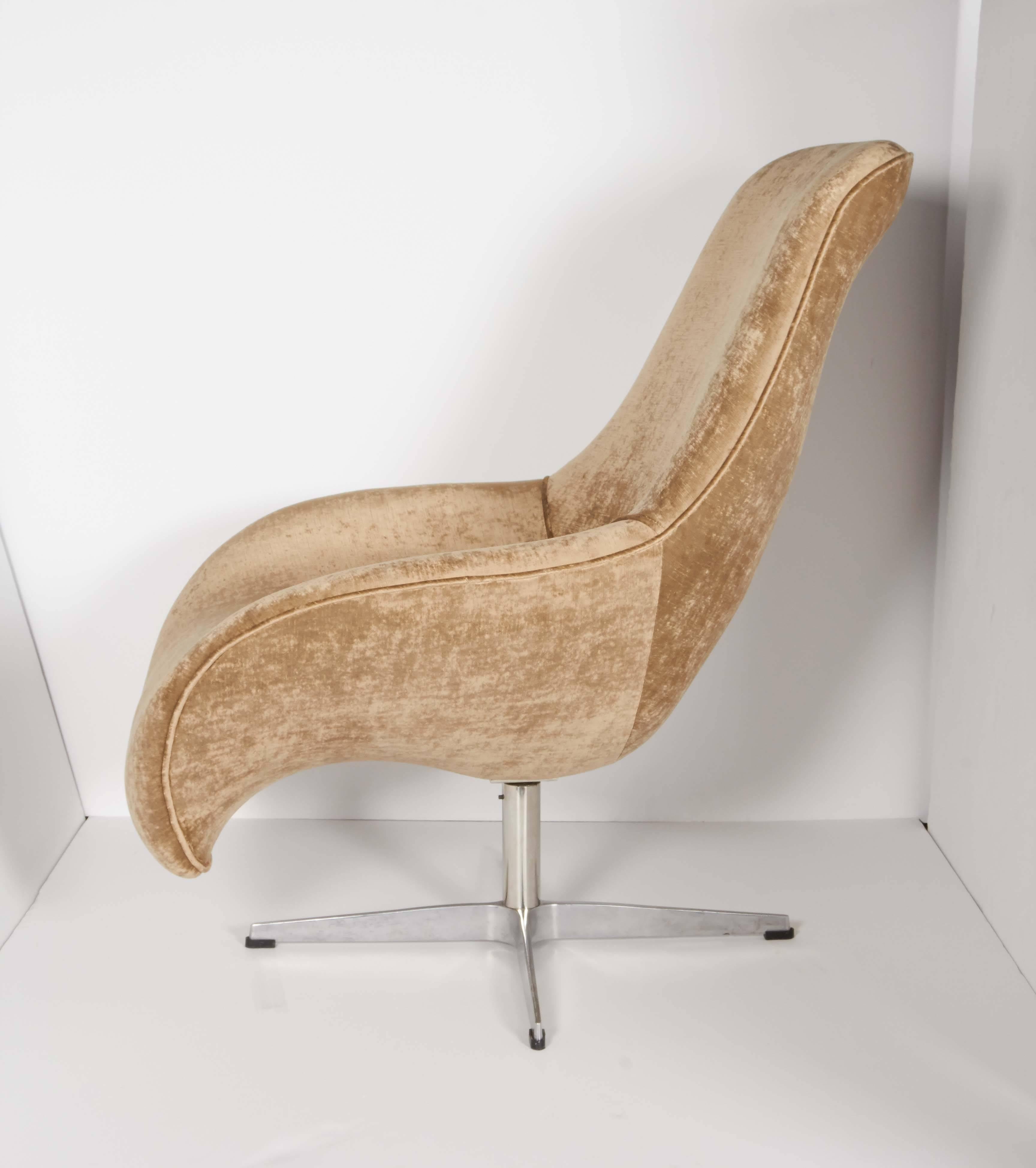Outstanding modernist lounge chair or scoop chair with curved form. Newly upholstered in luxe metallic taupe velvet. The chair features swivel seat and has 