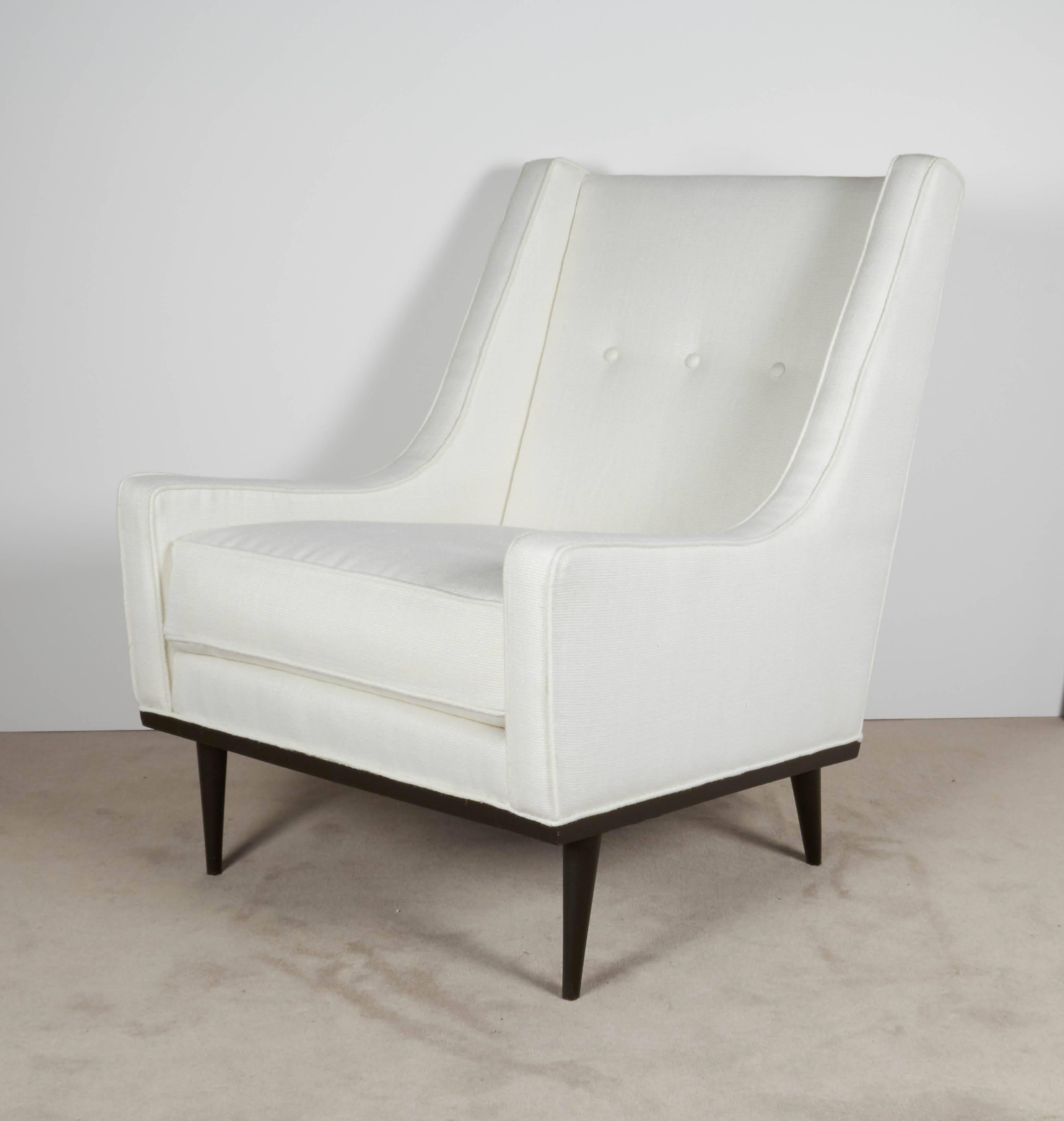 A lounge chair by Milo Baughman, circa 1960s upholstered in white cotton linen, with high button tufted back and sloped arms, on ebonized wood base and tapered legs. An early example of the work Baughman had designed for James Inc., the chair