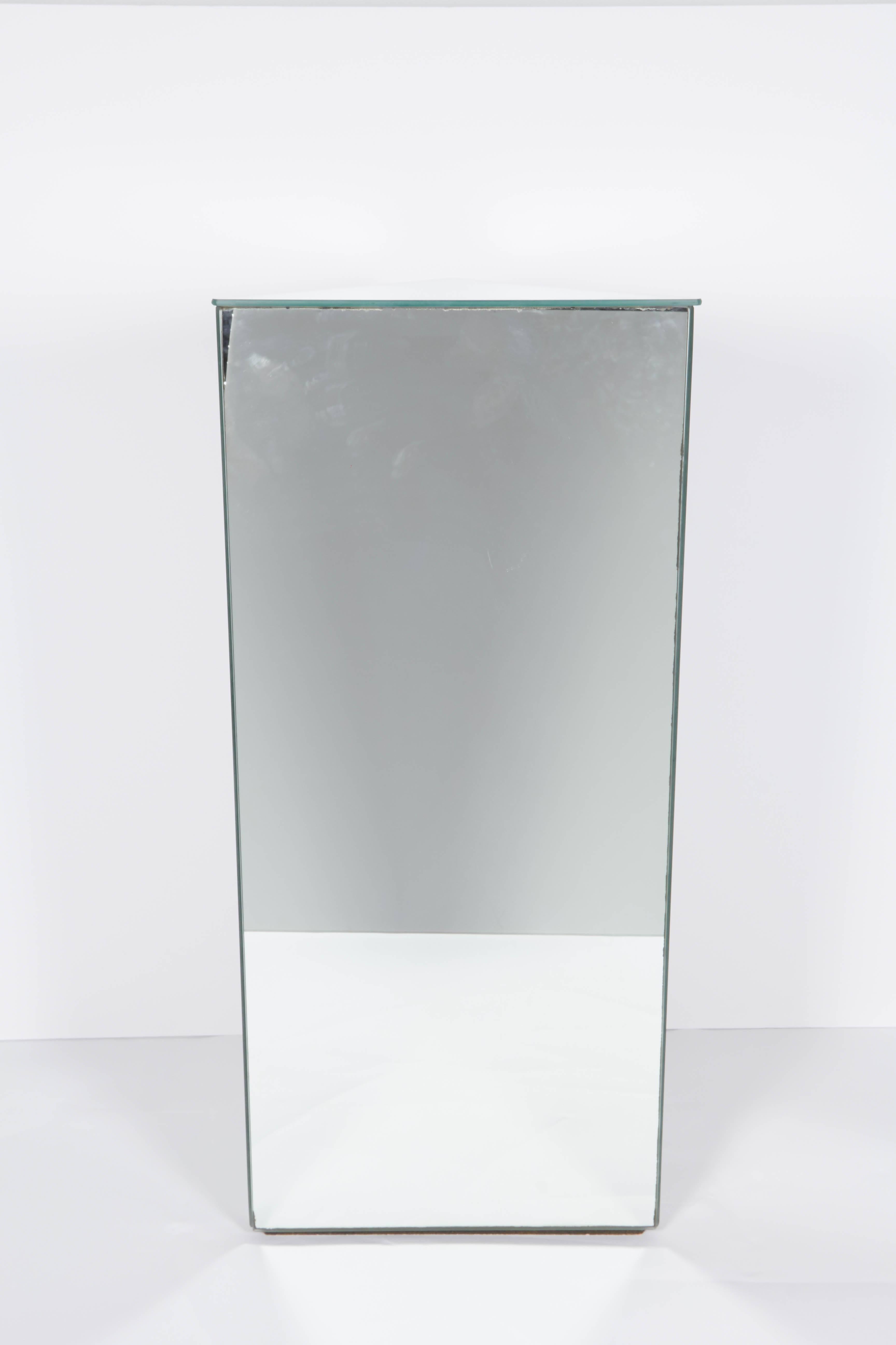 A vintage triangle pedestal, produced circa 1970s, with mirrored panels to the top and three sides, against a wooden base. Other than some presence of age appropriate wear along perimeter of glass, including minuscule silvering, this piece remains