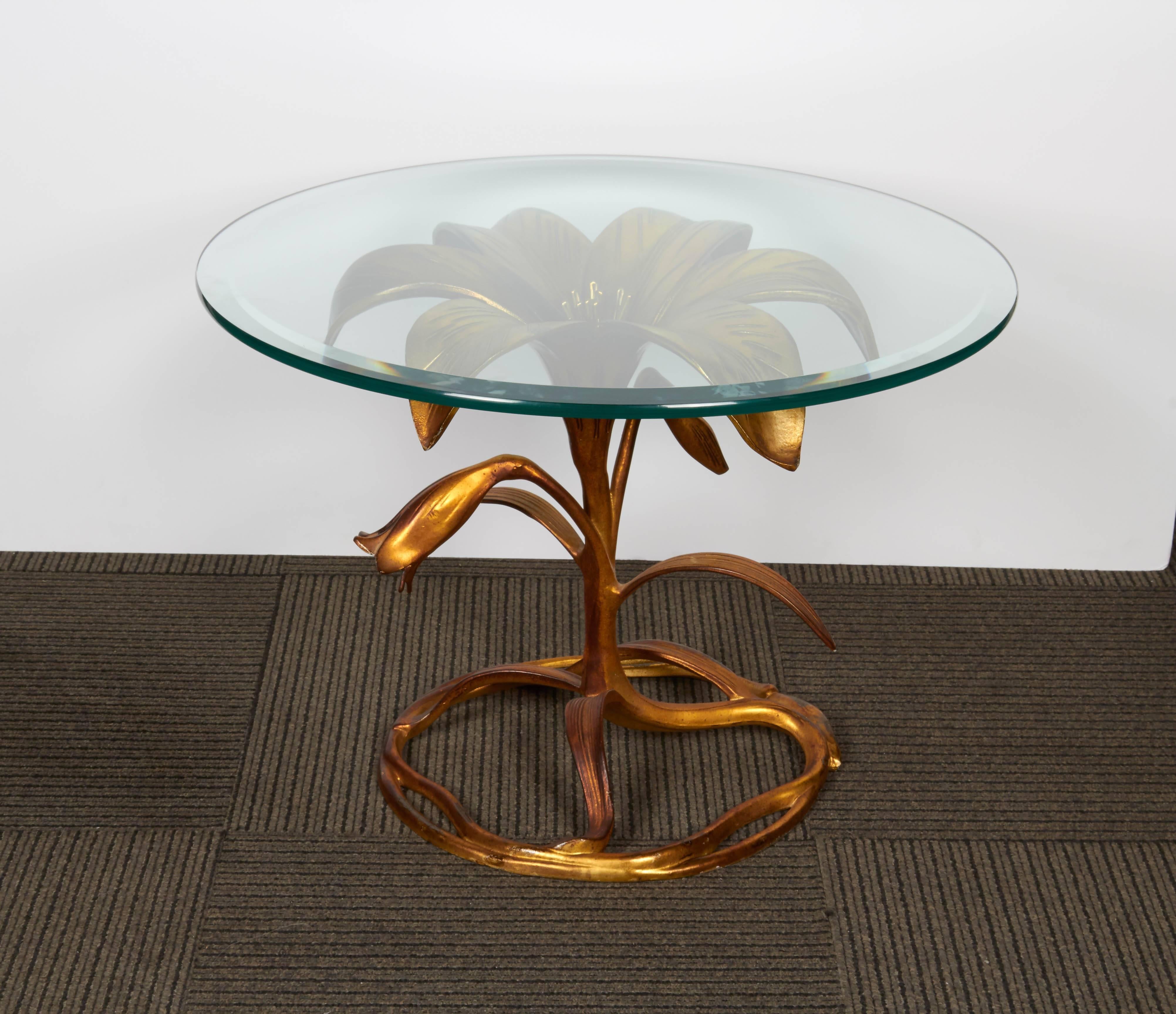 A sculptural table by Arthur Court, produced circa 1960s with a round, beveled glass top on a gilt metal base, whimsically designed as a curling lily. Very good vintage condition with minimal wear to gilding, consistent with age; dimensions provided