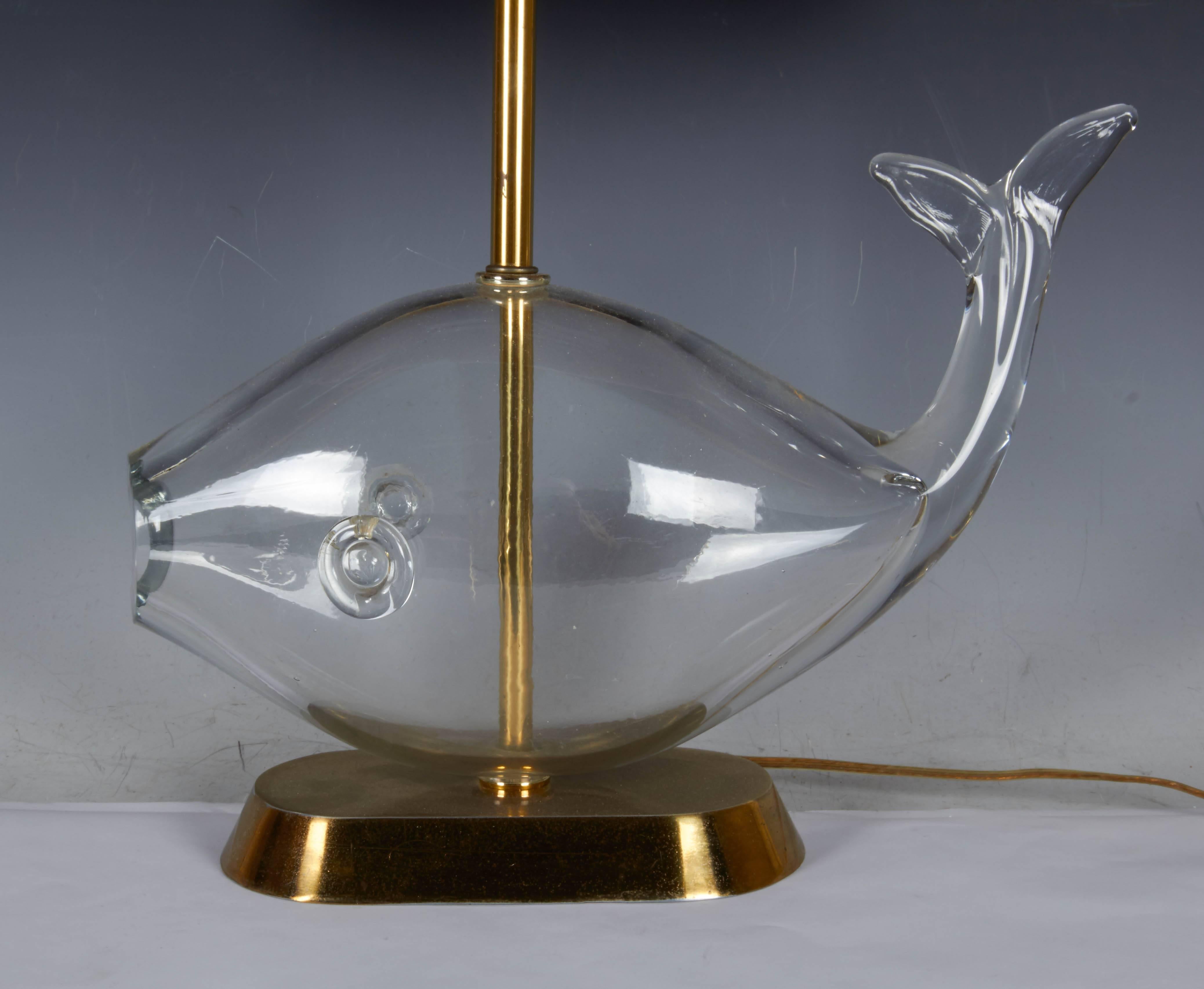 This vintage table lamp by Blenko comes with a single socket and the original string shade, above a sculptural fish in hand blown clear glass, mounted on a brass stem and base. Wiring and socket to US standard, requires a single Edison base bulb.