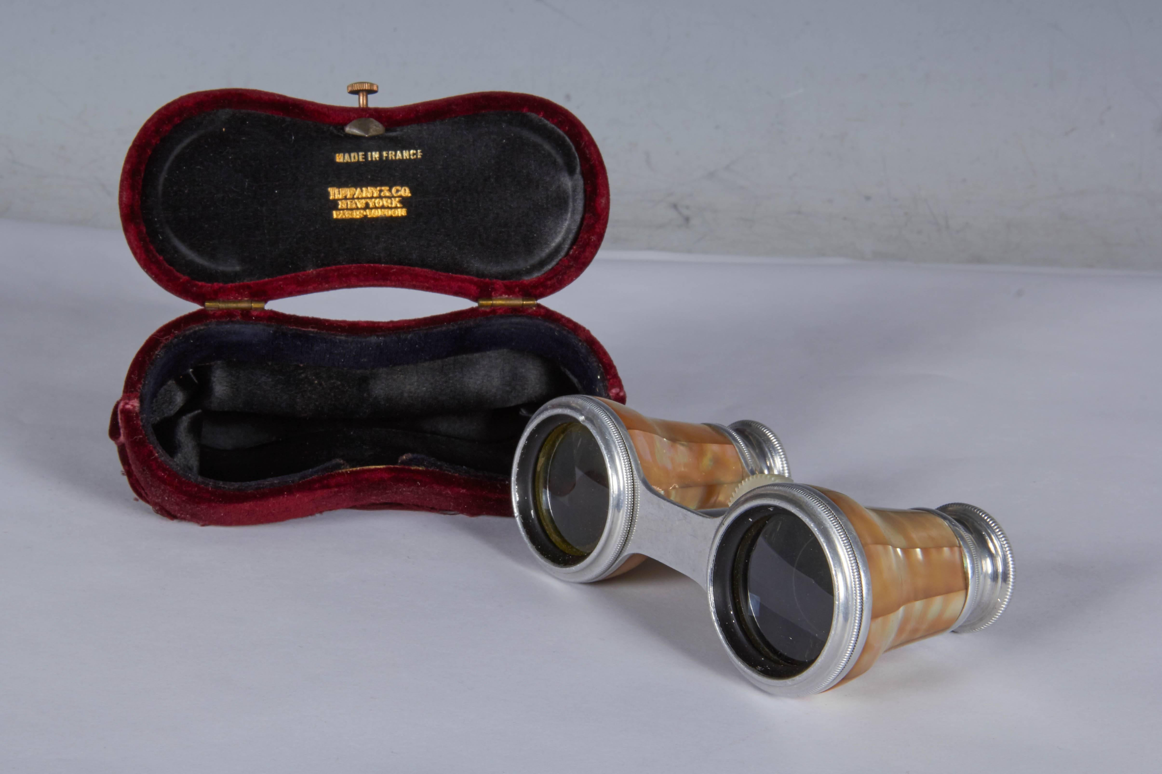 A pair of Tiffany opera glasses produced in France, circa 1870s, the binoculars in metal and veneered with mother-of-pearl, including red velvet case with braided rope handle and clasp. Markings include engravings [Maison de L'Ing Chevallier Optn/