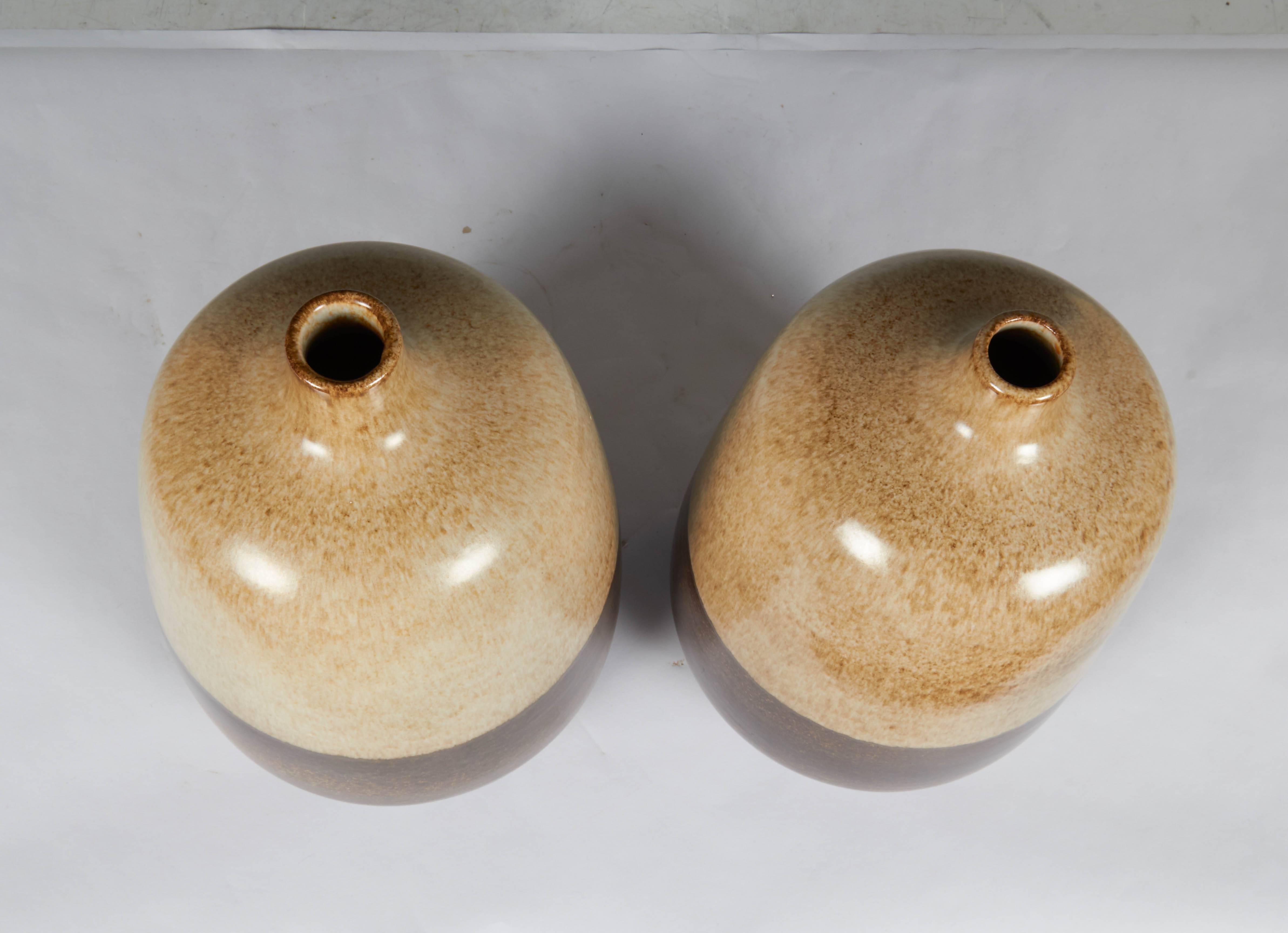 A pair of unmatched bottle form ceramic vases by Italian designer Alvino Bagni for Raymor produced, circa 1960s, each with mottled two-tone glazes, in beige and brown. Marks include original Raymor label, with codes [4437 BAH/4437 BAG]. Very good