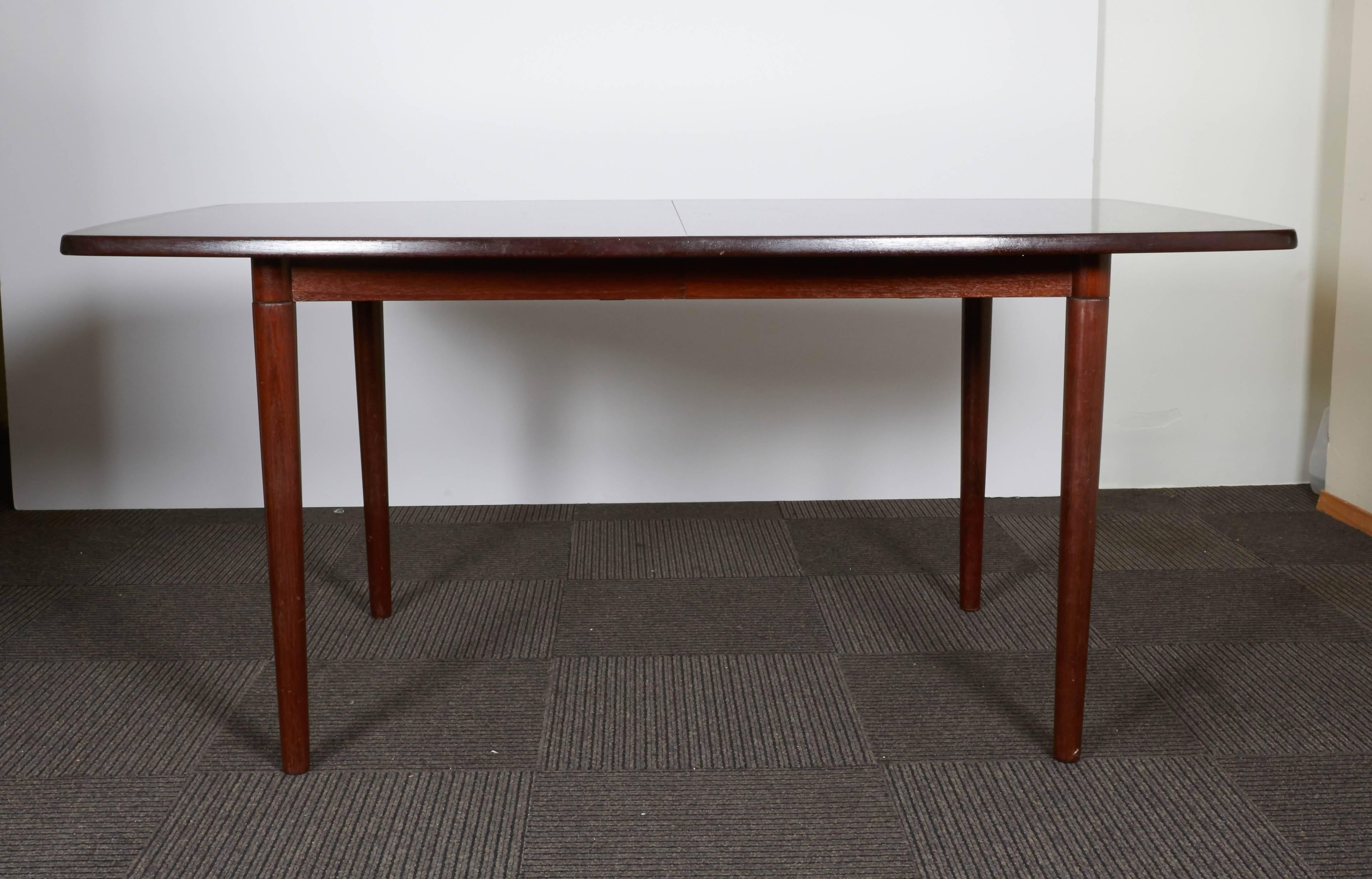 This 1960s Scandinavian modern style dining table by Niels Otto Møller, comes in beautifully polished rosewood with gently rounded sides and veneer detail to perimeter, on round tapered legs. Included are two extensions leaves, each 16.5