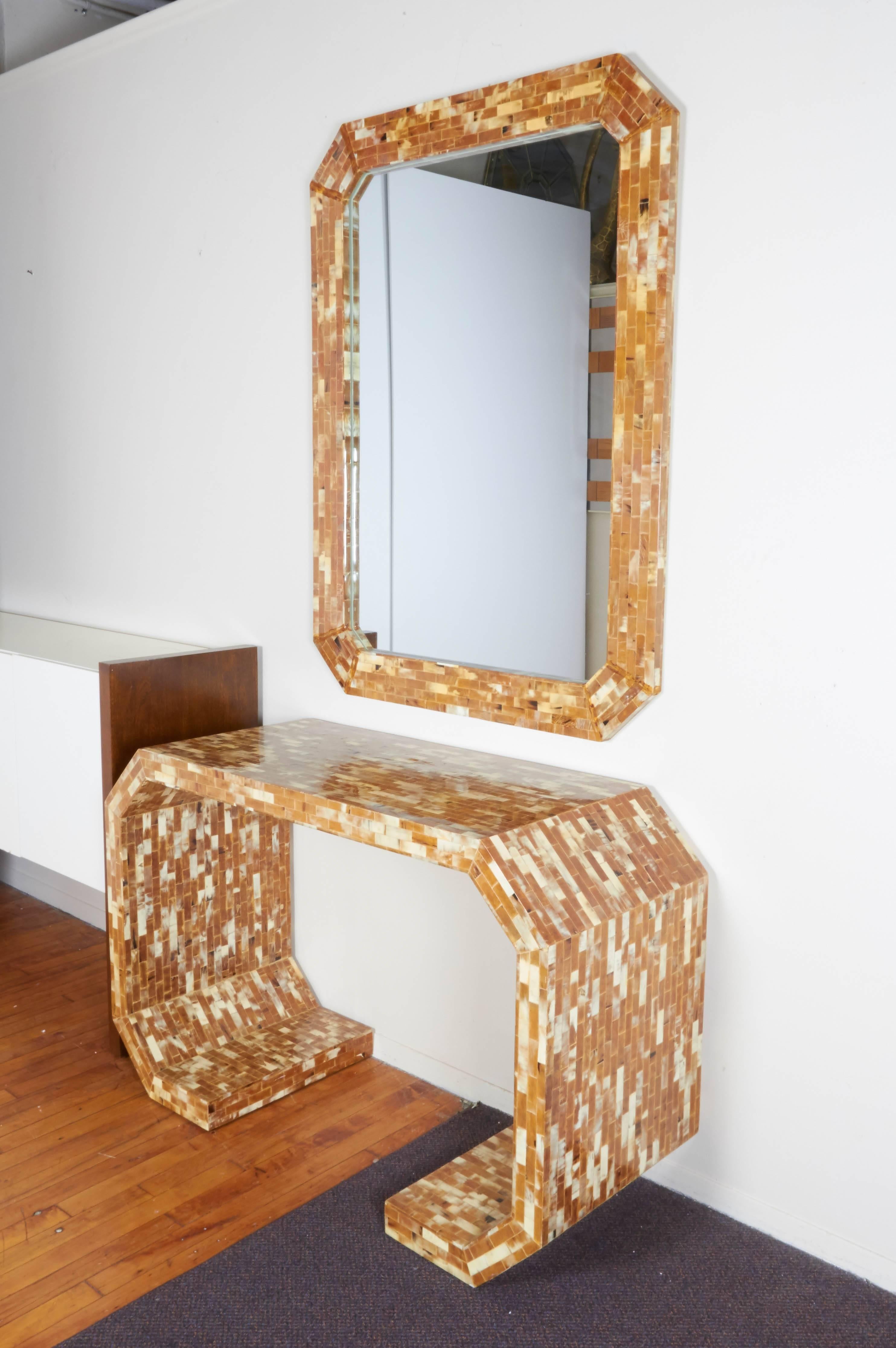 This matching console table and mirror, produced circa 1970s, closely following the style of designer Karl Springer, come veneered in multi-toned tessellated Horn, against highly geometric, octagonal form frames. Markings include [Handmade in