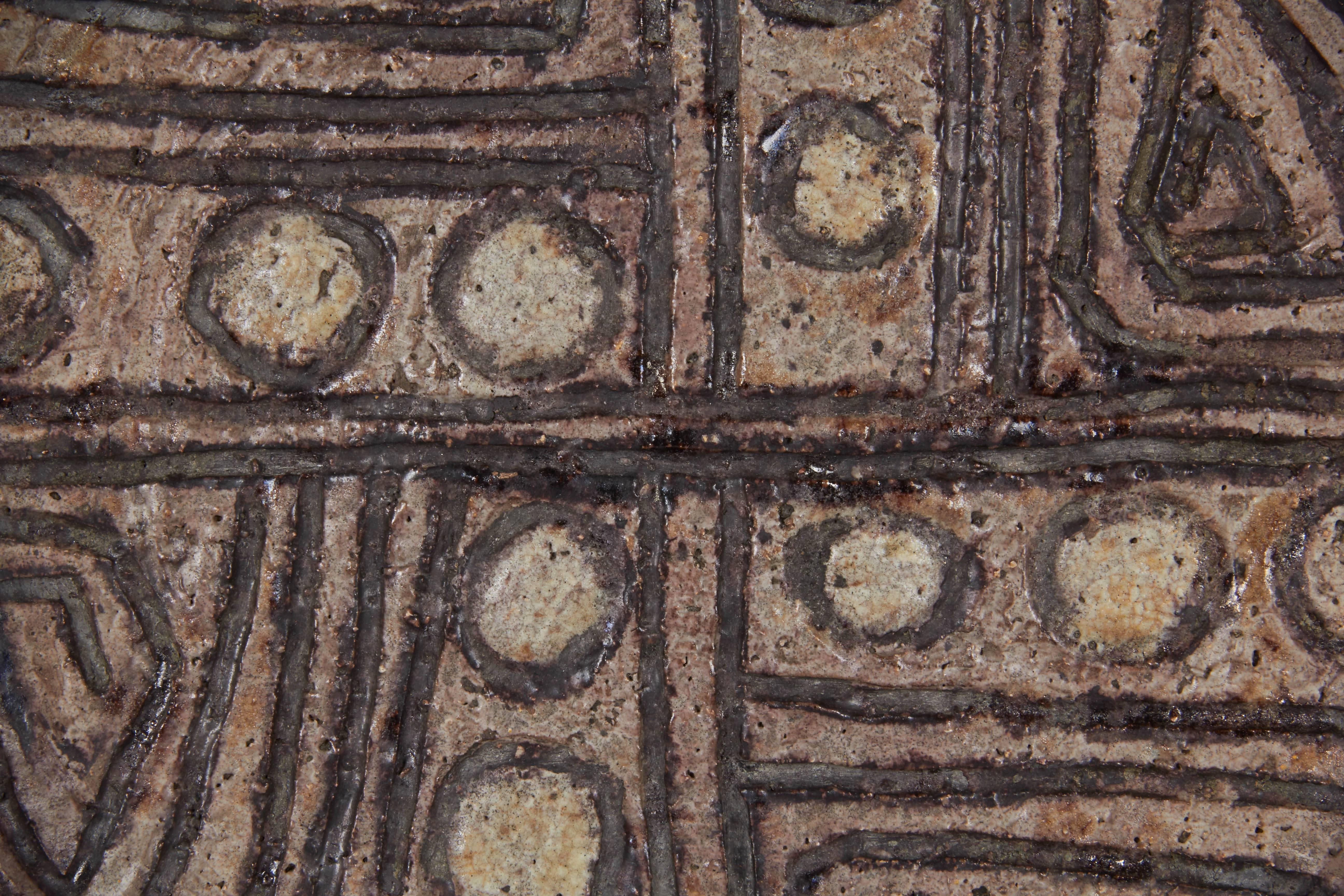 A vintage hand-thrown Studio Pottery plate, produced in Europe, presumably French in origin, glazed and incised with roughly applied geometric shapes and lines. Signed [MV ermes] to the underside of the plate. Excellent condition, wear consistent