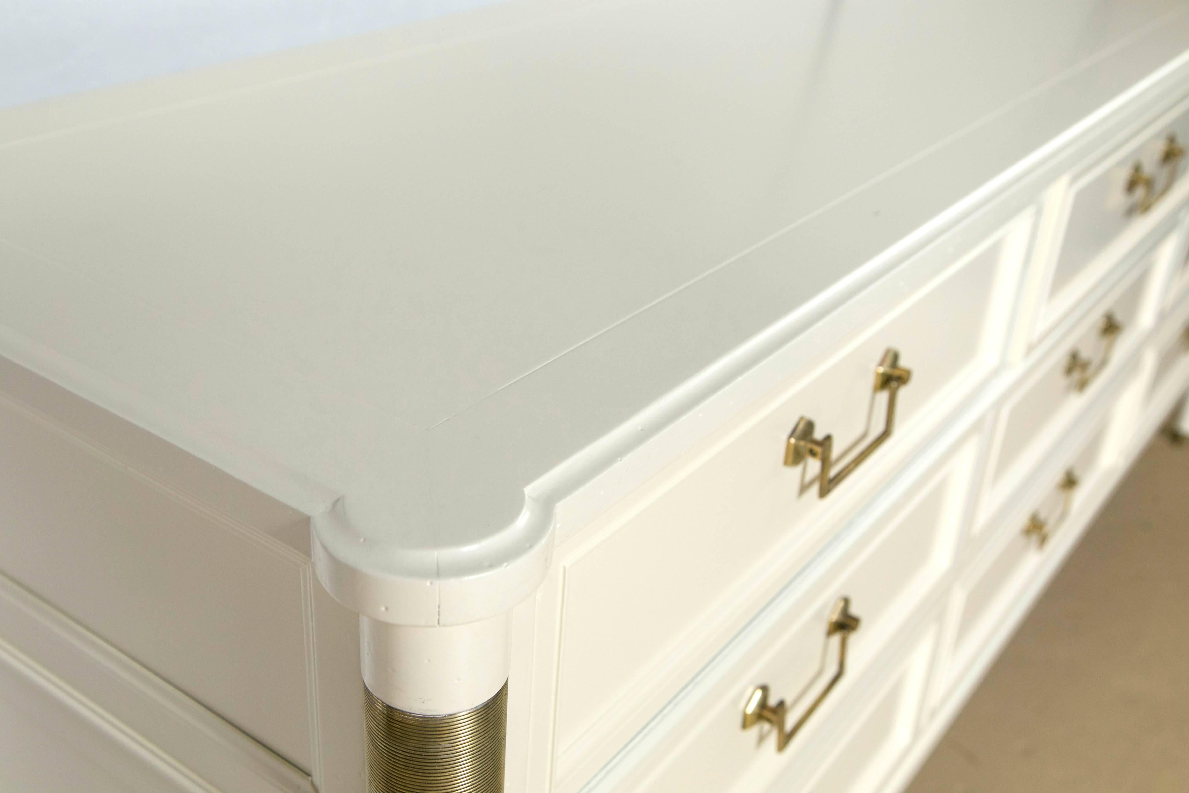 A fine Baker Furniture Company white lacquered nine-drawer dresser or commode. The oak secondary chest is a prime example of detail to workmanship. The Louis XVI style chest has bronze moldings and cookie cutter corners. Having nine drawers overall