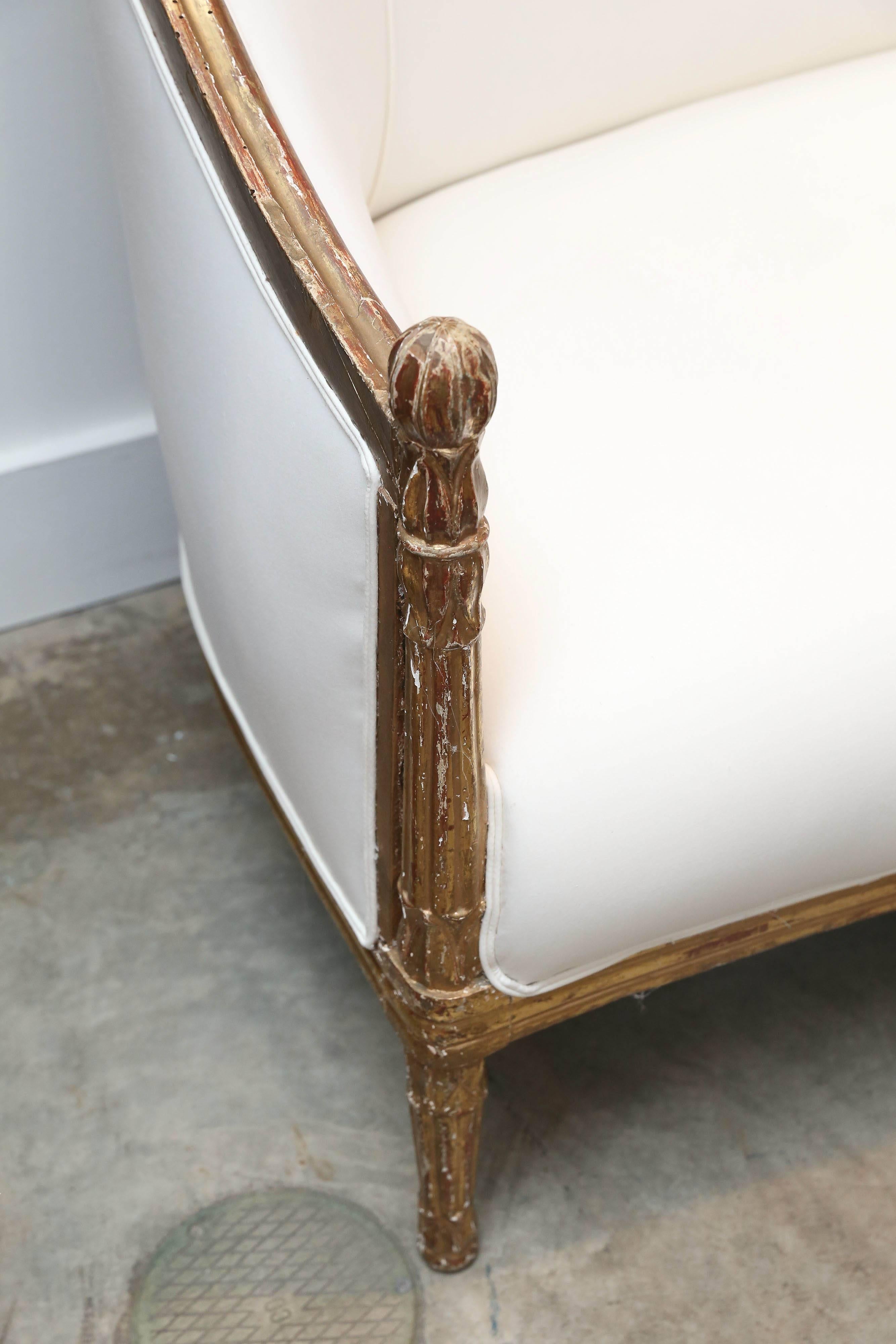 Antique 19th century giltwood settee that we have reupholstered. Details on the carved wooden frame include a floral detail and round post handles on the arms. Beautiful gilt color.