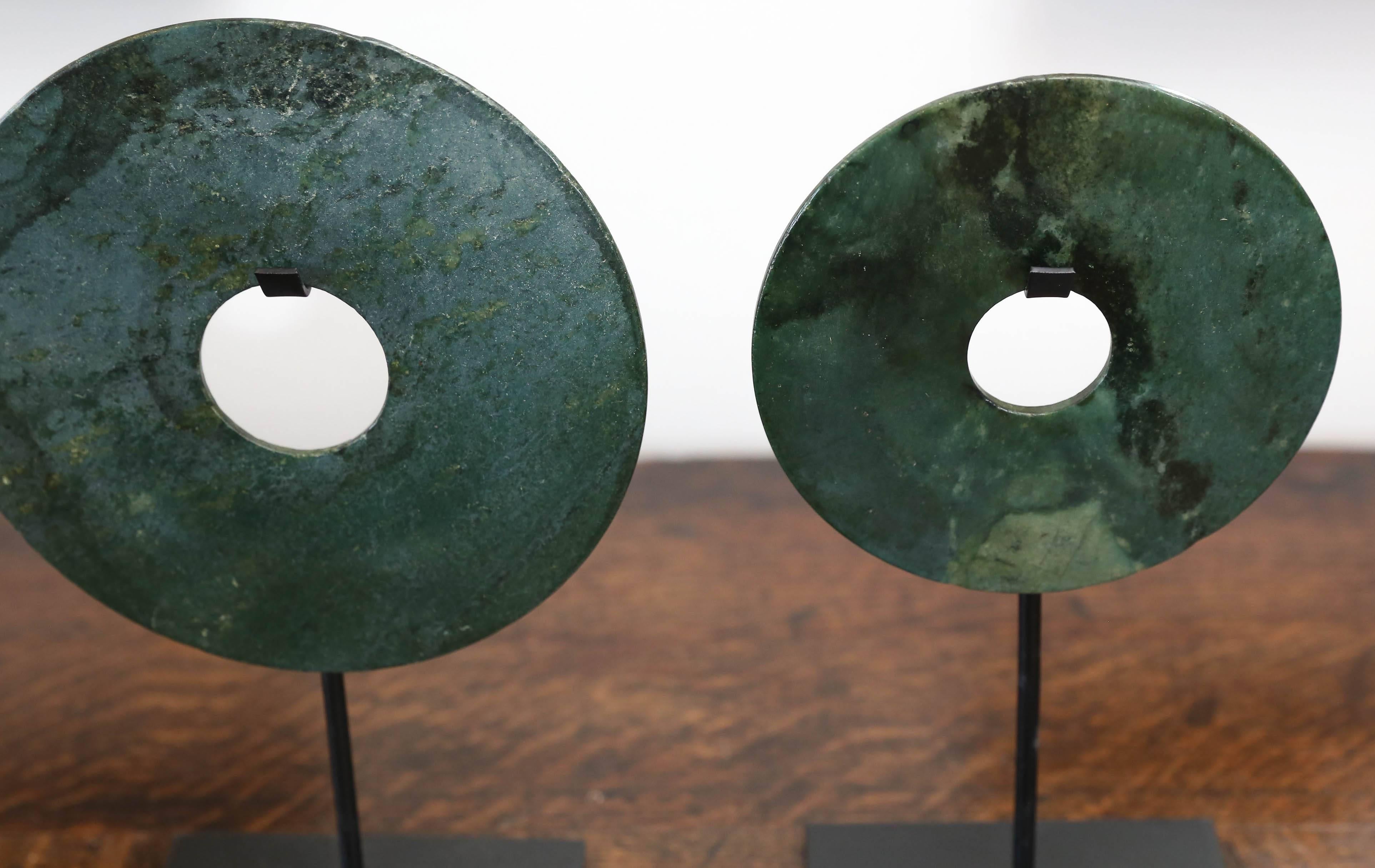 This is a set of three Bi Chinese stone flat disks with a hole in the centre on iron stands. The Bi disk was a symbol of heaven or of the sun. It was commonly used by nobles as a ceremonial utensil during sacrifices to the gods and to ancestors,