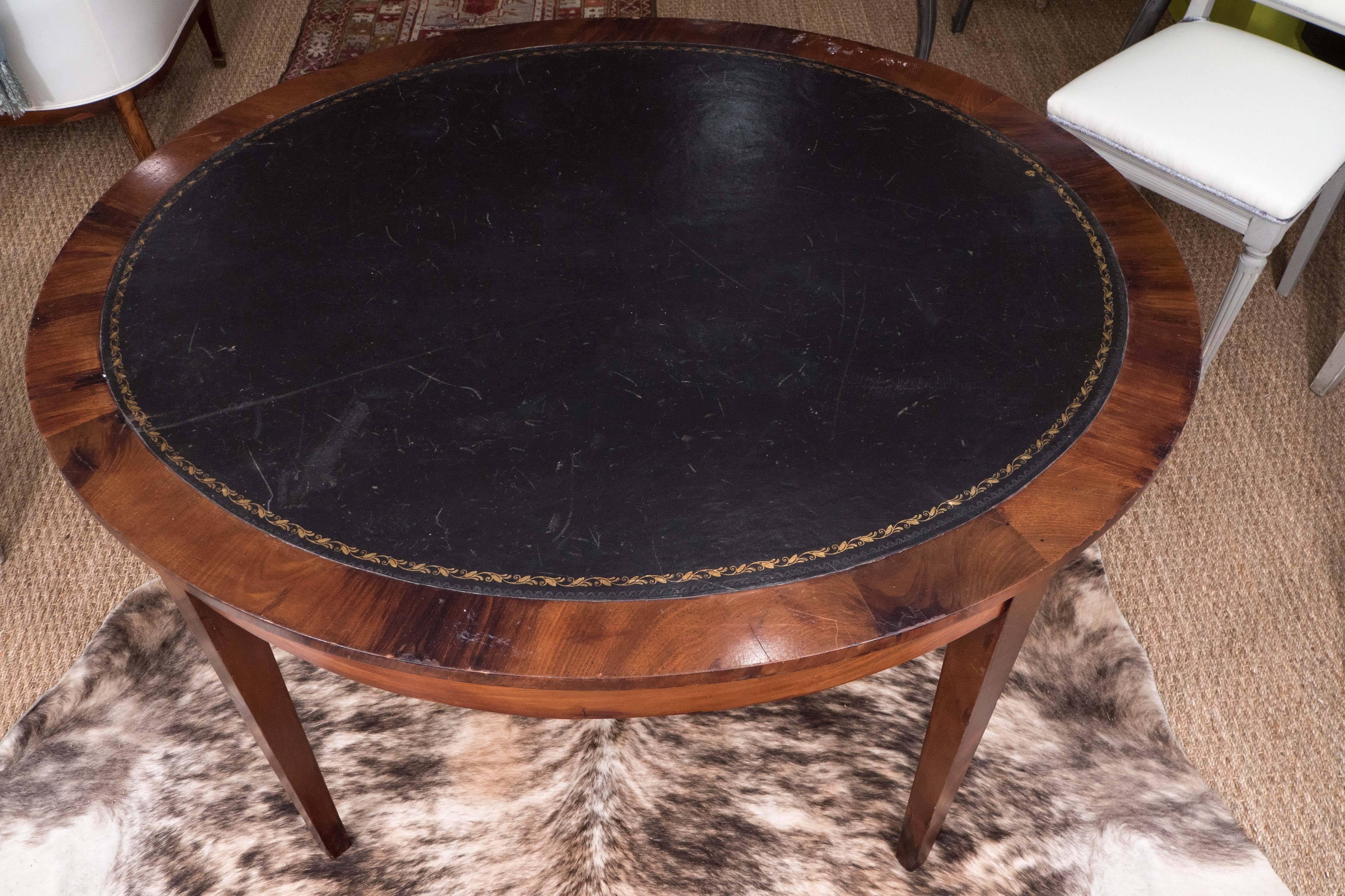 This handsome, slightly oval French table is not only beautiful, but is quite versatile. In mahogany with clean lines, a simple apron and straight, slightly tapered legs, the table has developed a lovely patina and looks fabulous with the black,