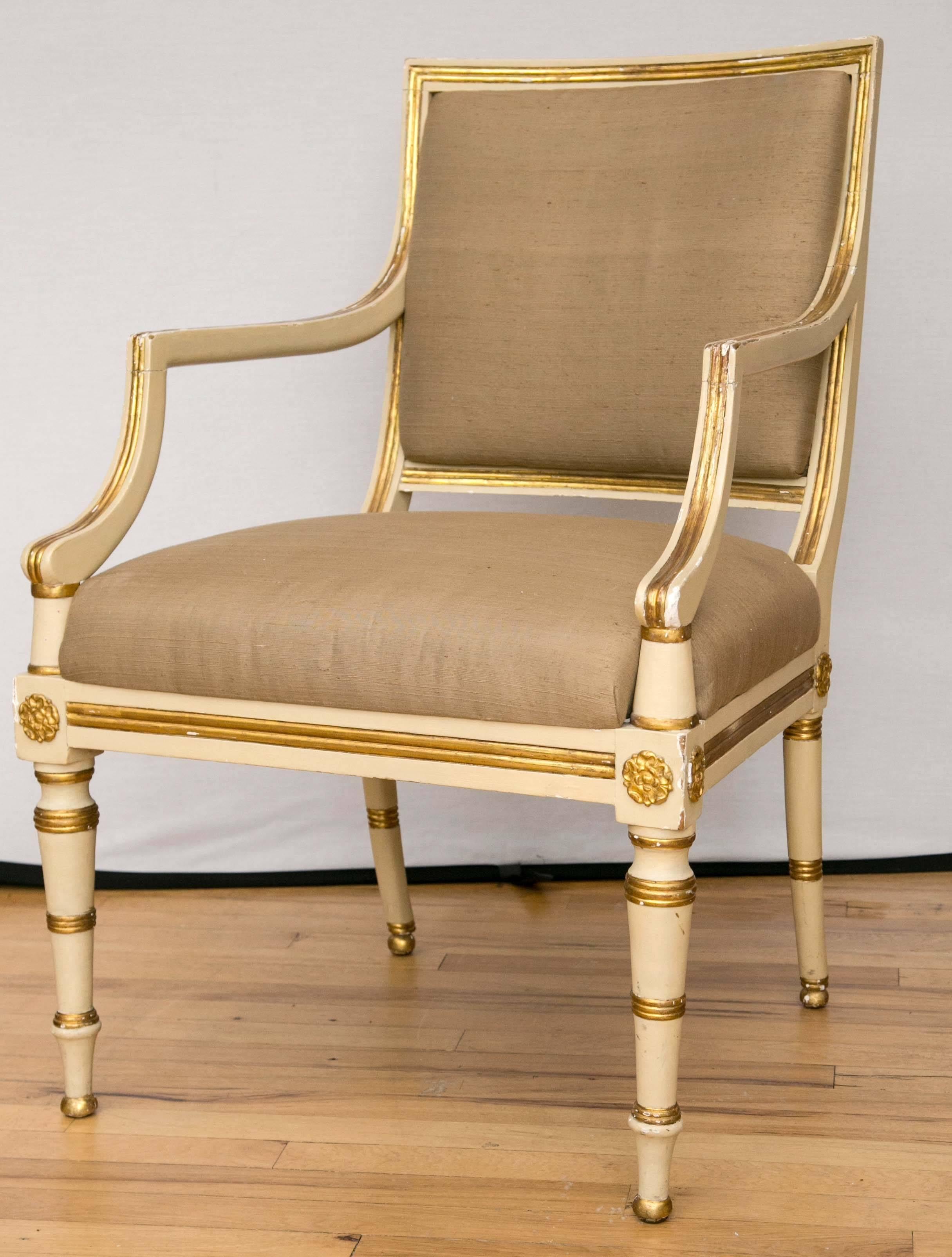 An elegant pair of parcel-gilt and cream painted armchairs with upholstered seats and backs.