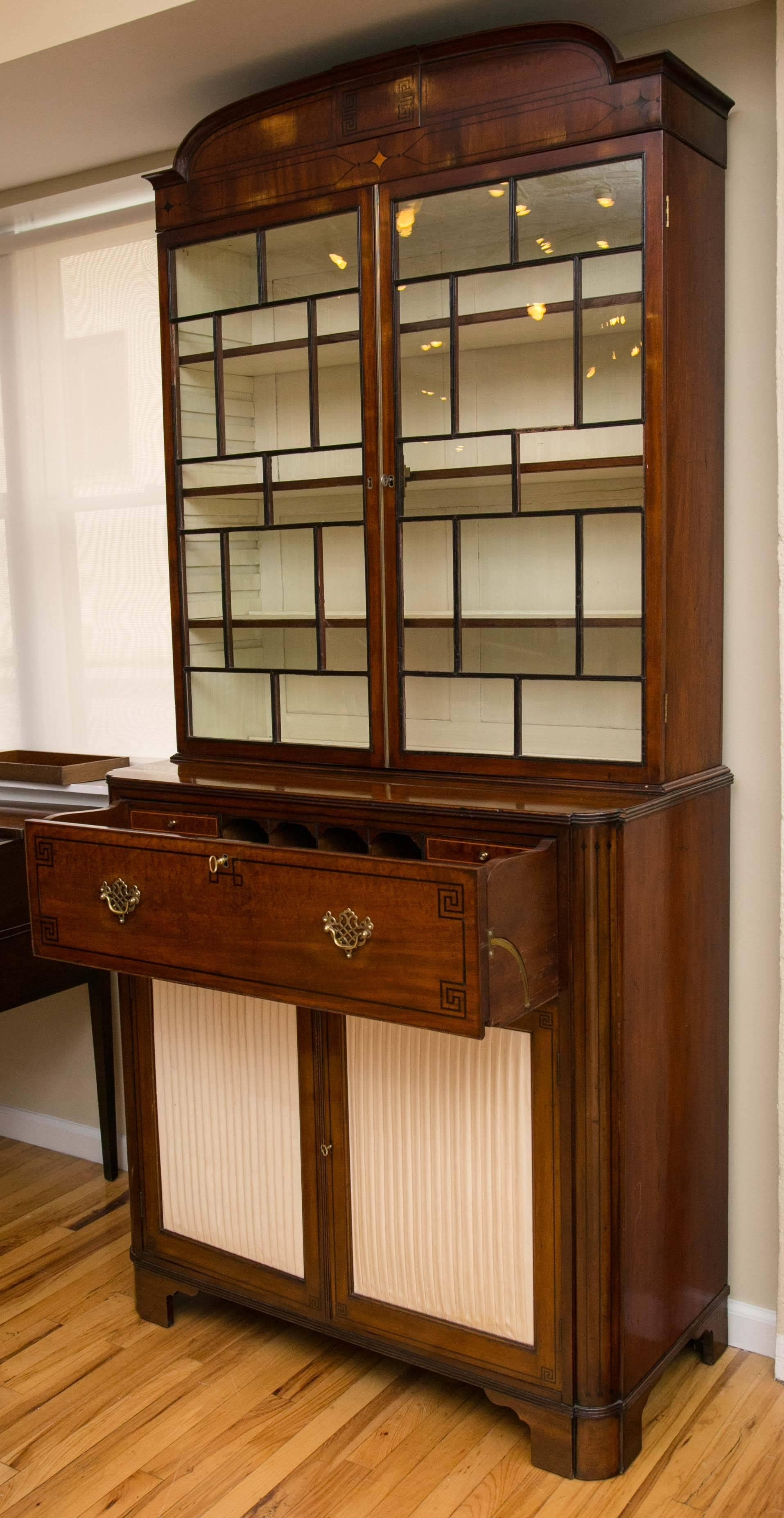 Mahogany secretaire bookcase, domed cornice with applied mouldings over geometric glazed doors enclosing adjustable shelving. Secretaire drawer inlaid with an ebony Greek key motif and fitted with arrangement of pigeon holes and small satinwood