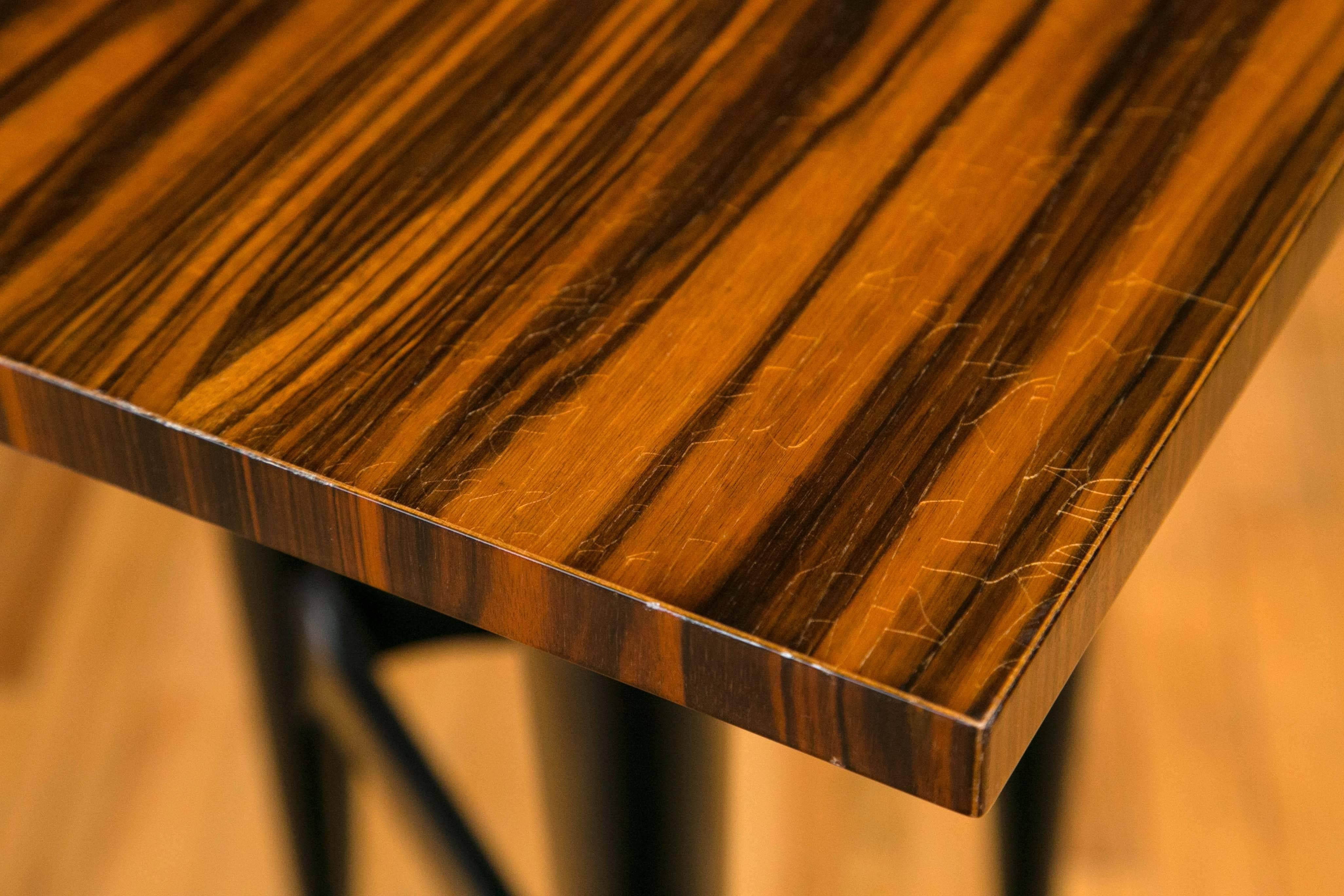 Panels of Macassar ebony cover the desk top which sits on tapering tripod blackwood legs. The face of the desk conceals three drawers, the center drawer containing compartments.