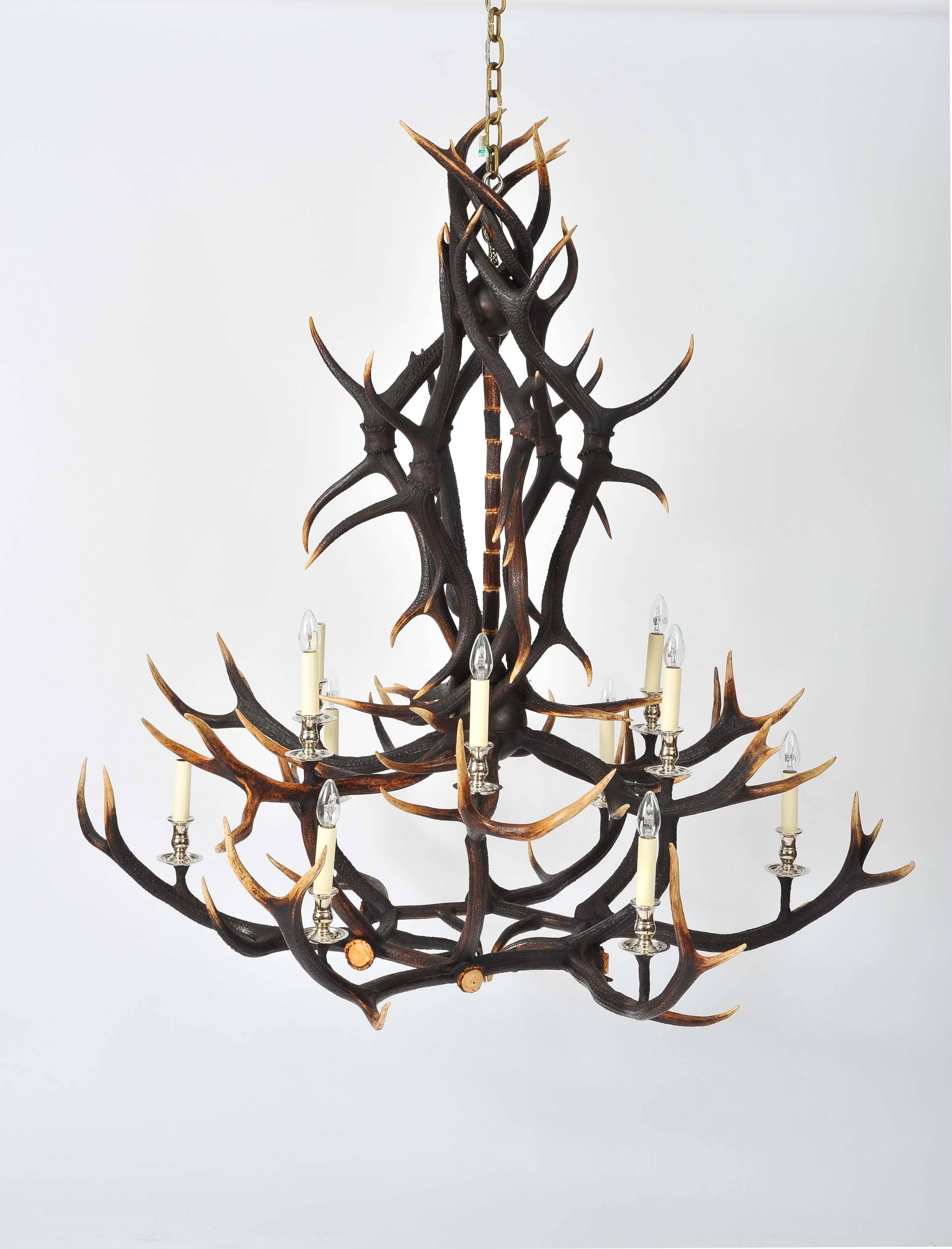 This outstanding antler chandelier was custom designed and made from naturally shed large red deer from Scotland. This unique light features two tiers and 12 candle styled lights with brass hardware. The hardware can also be done in nickel plate, if