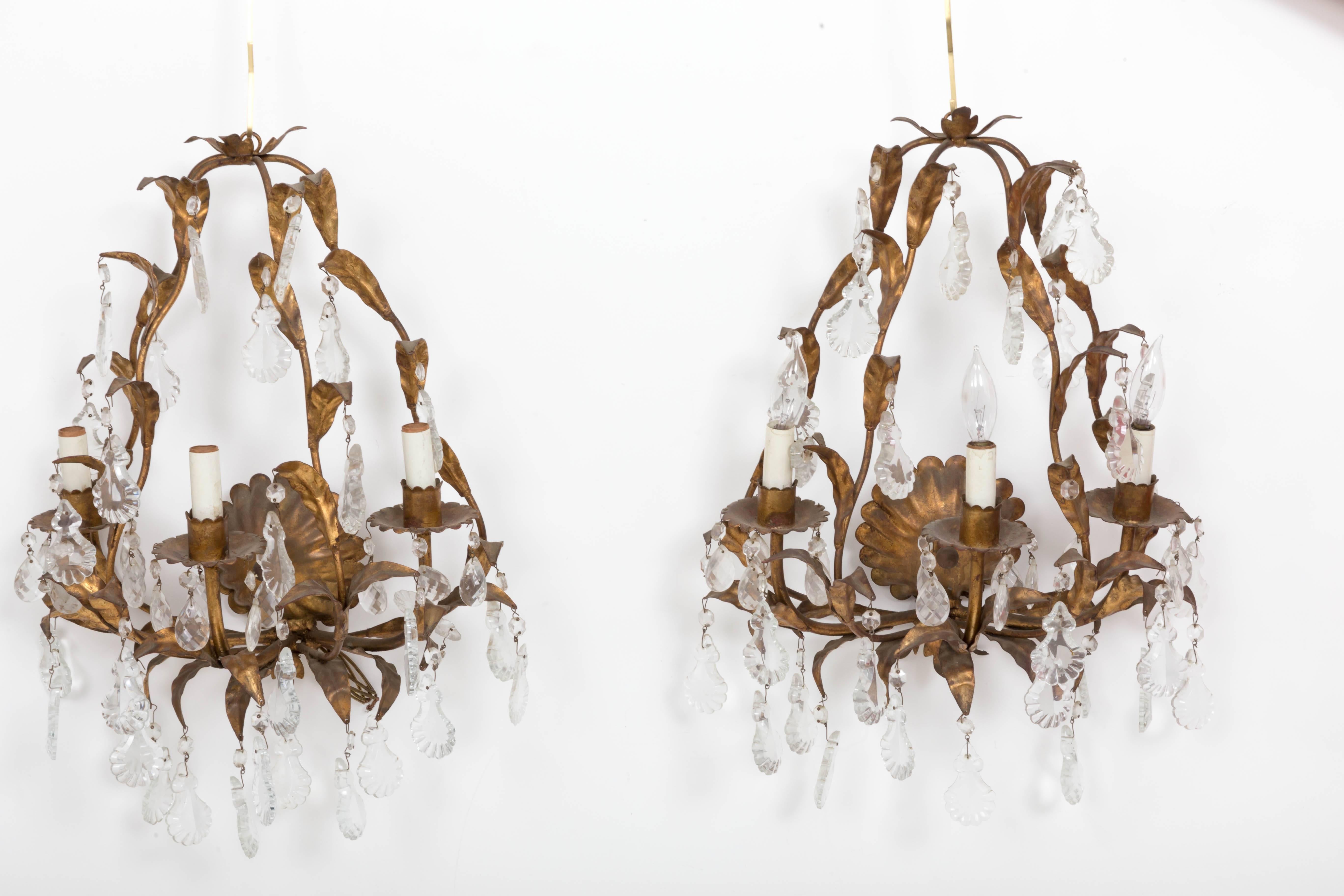Gilded brass leaf shape scrolled sconces with scallop shape crystals and faceted teardrop crystals.