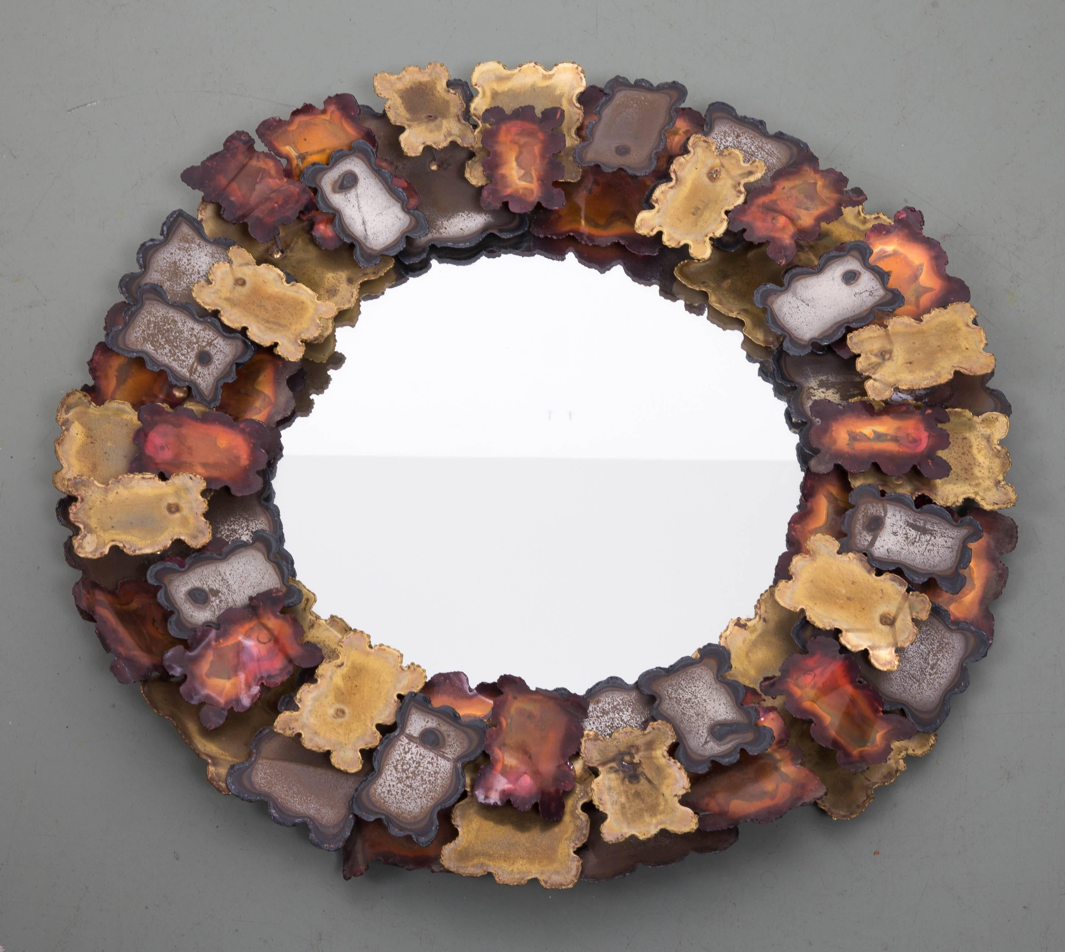 Patinated mixed metals forming two tiers around circular mirror.