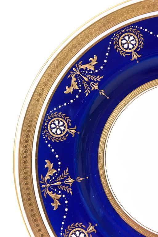 An elegant set of twelve dinner or presentation plates by the fine porcelain firm of Minton's of England. Custom ordered through the prestigious retailer of William Plummer, New York. These stunning plates feature white enamel 