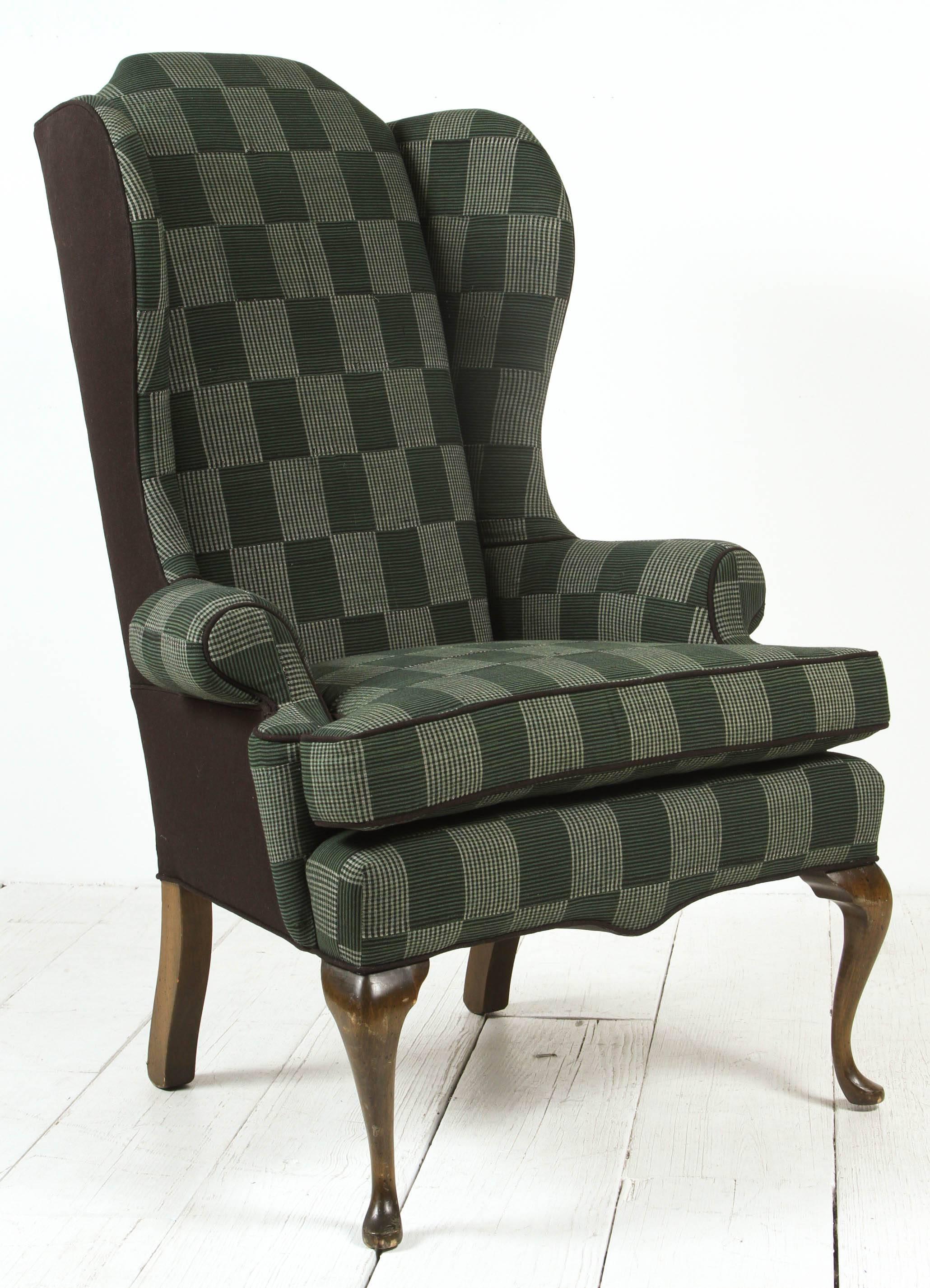 Classical wing chair with oak legs reupholstered in green plaid African fabric and black linen on the exterior.