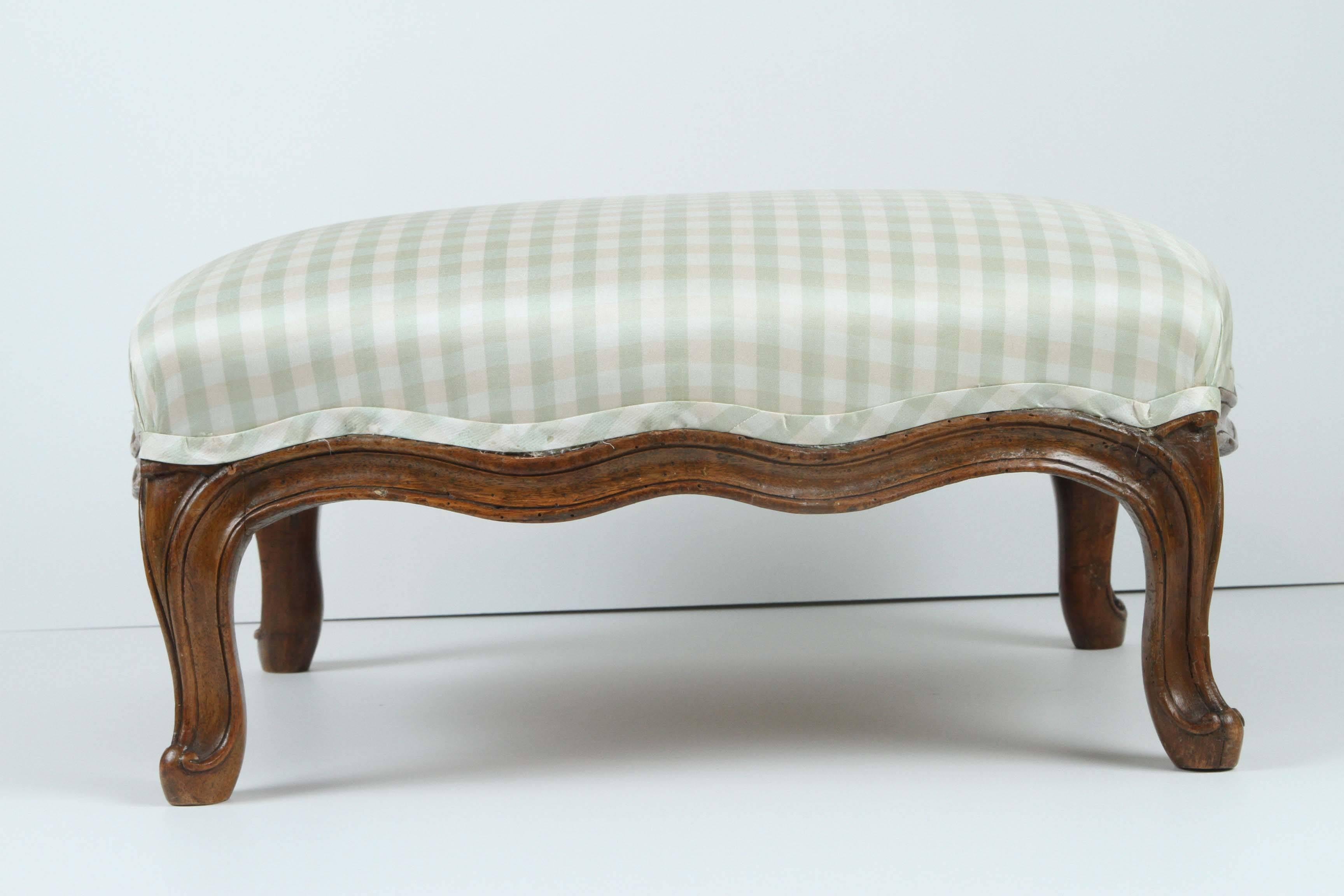 A French Louis XV footstool in beechwood with distinctive Rococo curves and carving.