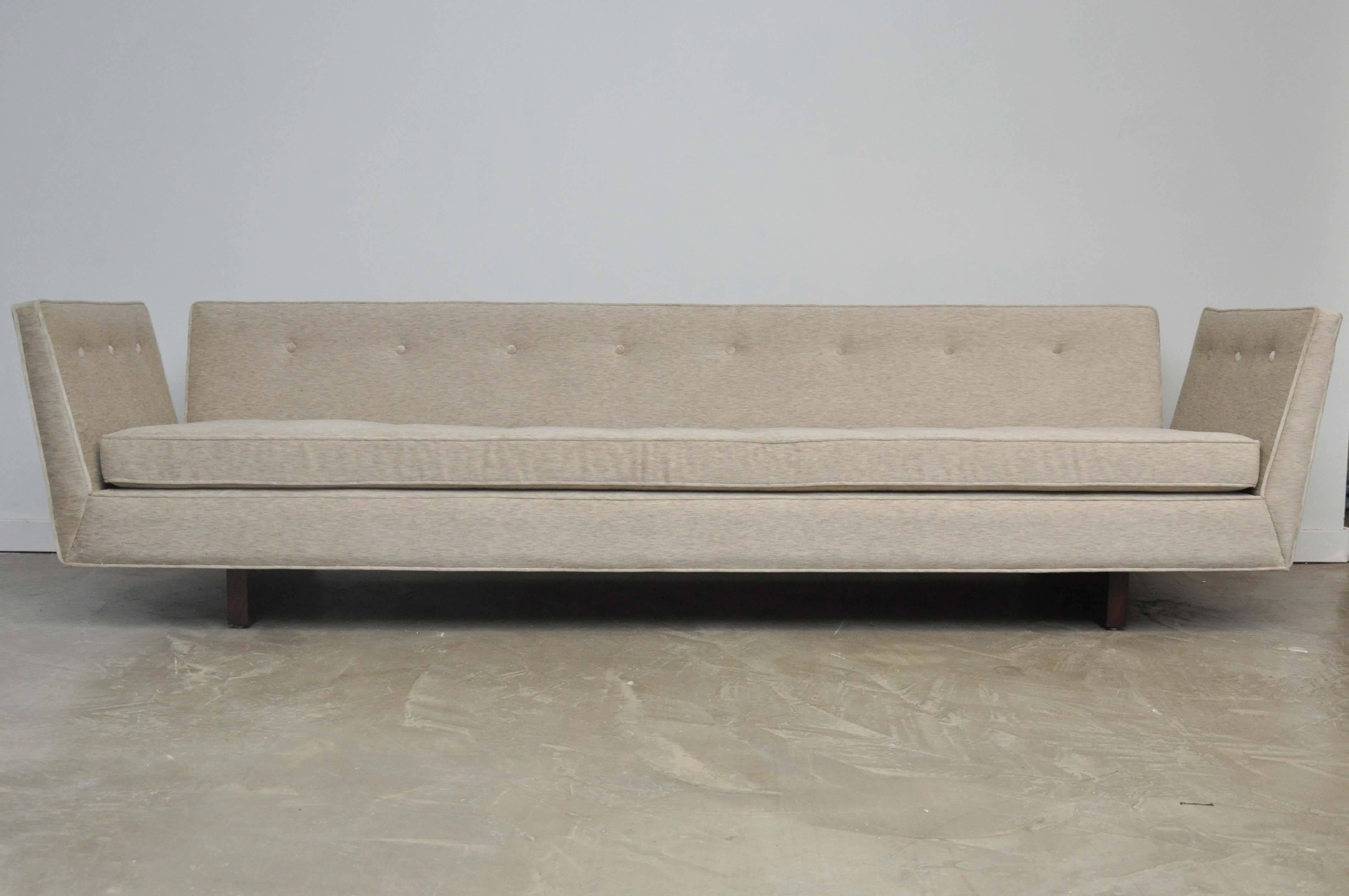 Large-scale open-arm sofa by Edward Wormley for Dunbar. Sculptural form sofa with exposed walnut legs coming up the back side of sofa. Fully restored and reupholstered in Italian velvet.