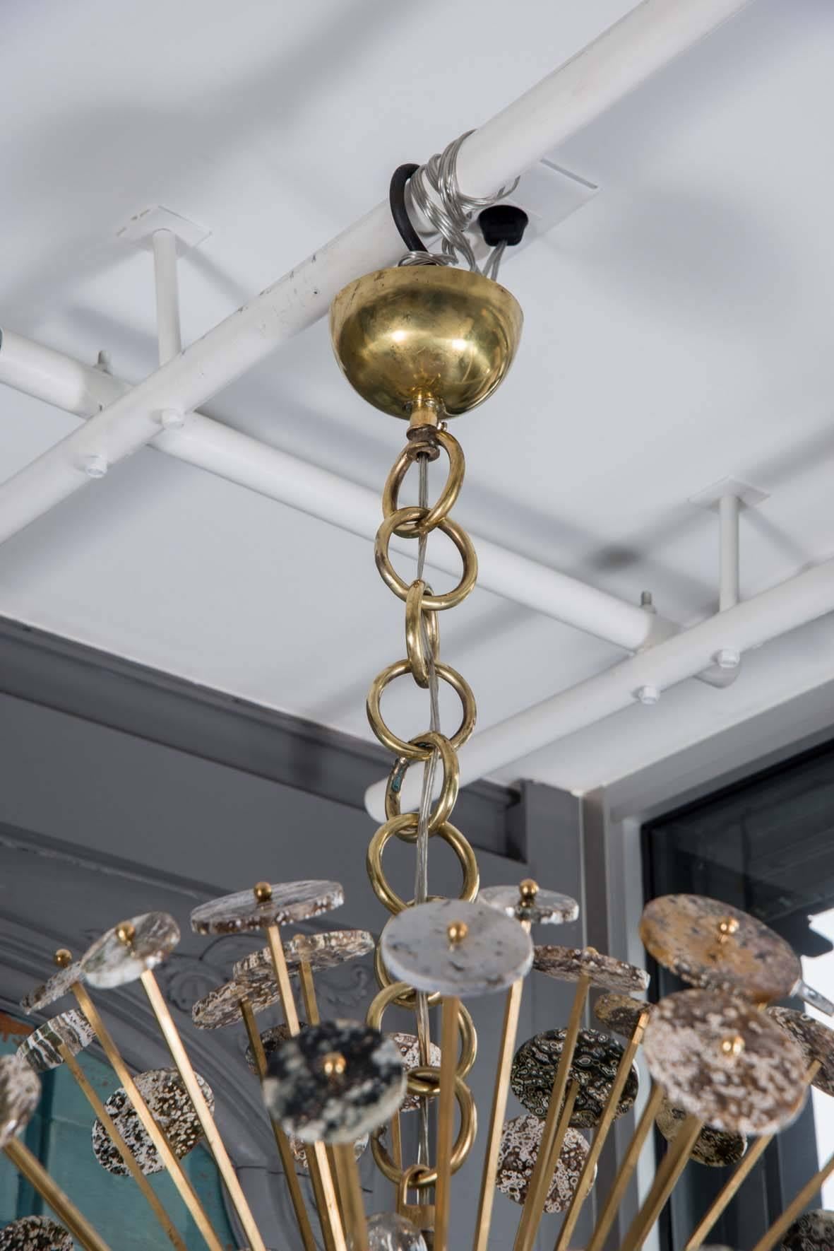 Unique chandelier designed by Glustin Luminaires.

Oval Sputnik shaped chandelier made of brass center and arms decorated by more than on hundred discs of ocean jasper stone.