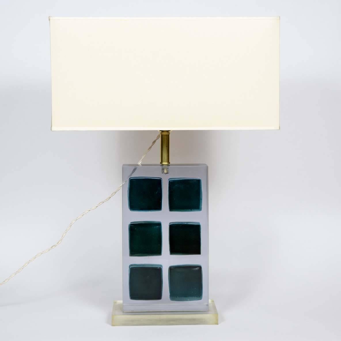 Interesting pair of lamps made of blue square Murano glass tiles trapped in a resin body. Resin feet and brass hardware.