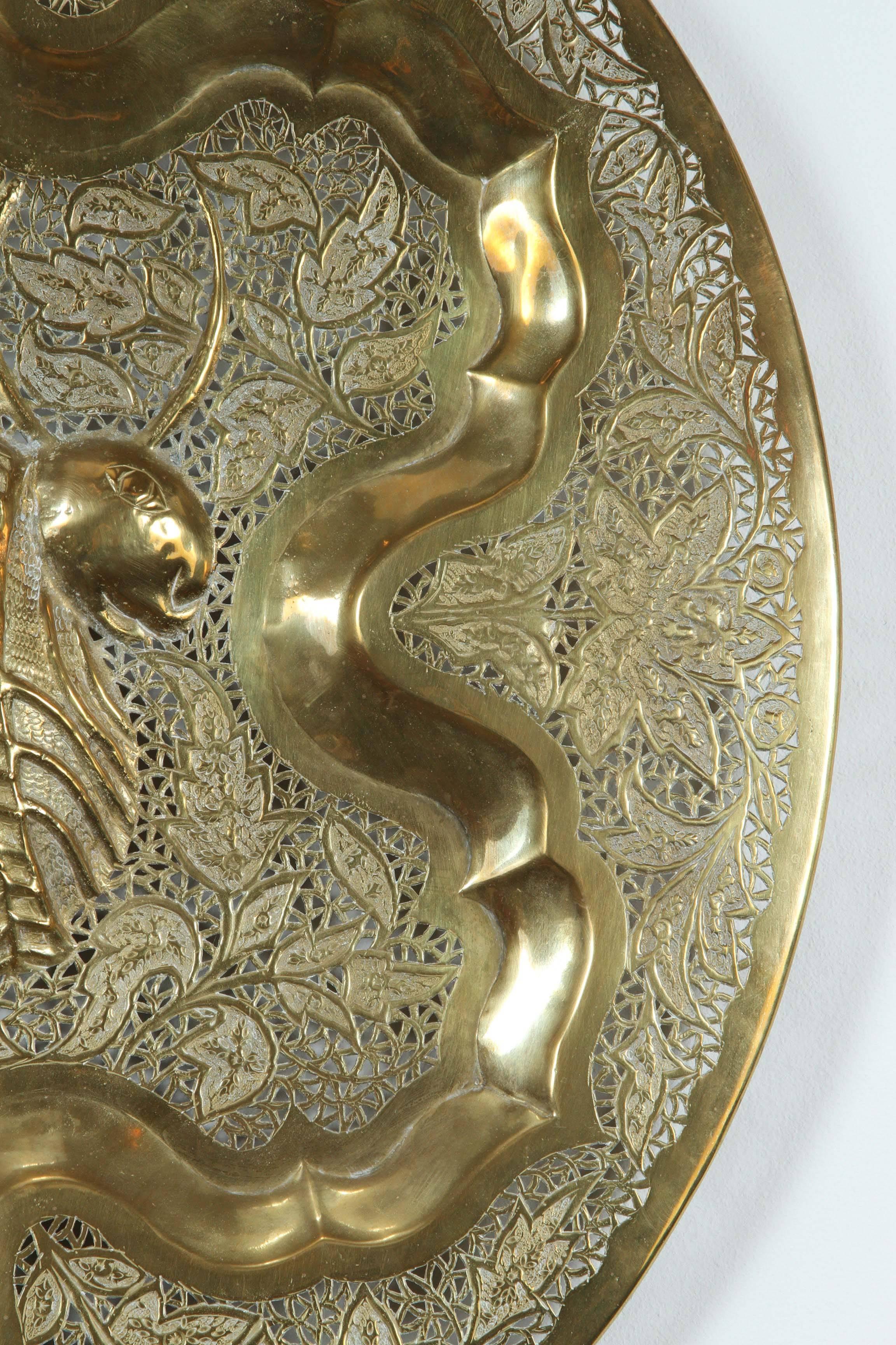 Anglo Raj hanging polished brass tray.
Finely hand-chased, hand-cut and hand-hammered with floral repousse designs.
The middle of the tray is a large ceremonial figure of a cow hammered.
Great brass decorative art object.
 
