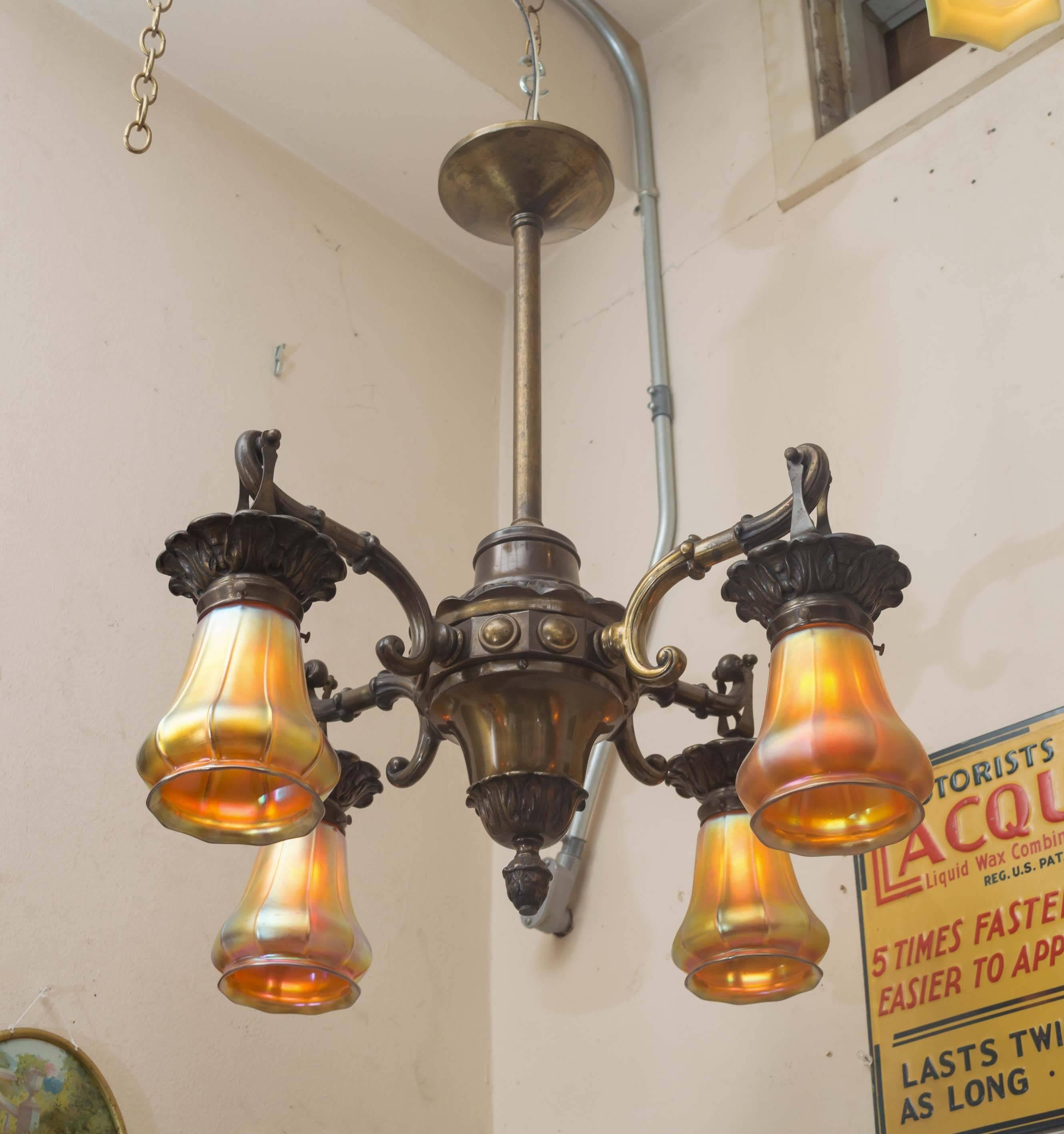 This very handsome four-arm chandelier is a fine example of quality craftsmanship that has long since disappeared. To enhance the beauty of this light there are four Steuben glass shades, and a wonderful warm original patina on the metal.