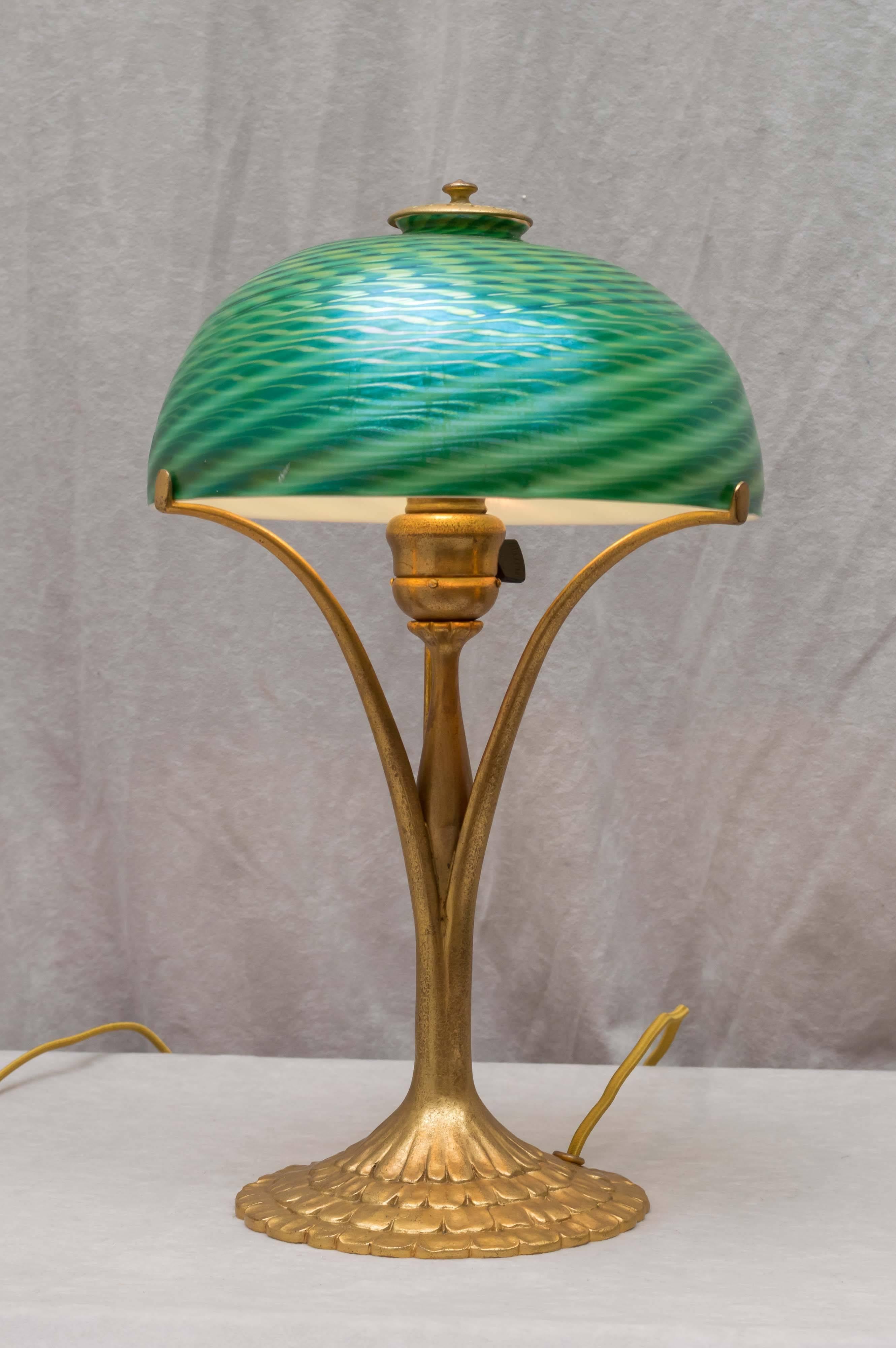 This wonderful little Tiffany lamp has a richly gilt patina bronze base and a beautiful handblown swirl shade. Both shade and base are signed and are guaranteed original. Not a reproduction. A great little lamp for a reasonable price in the Tiffany