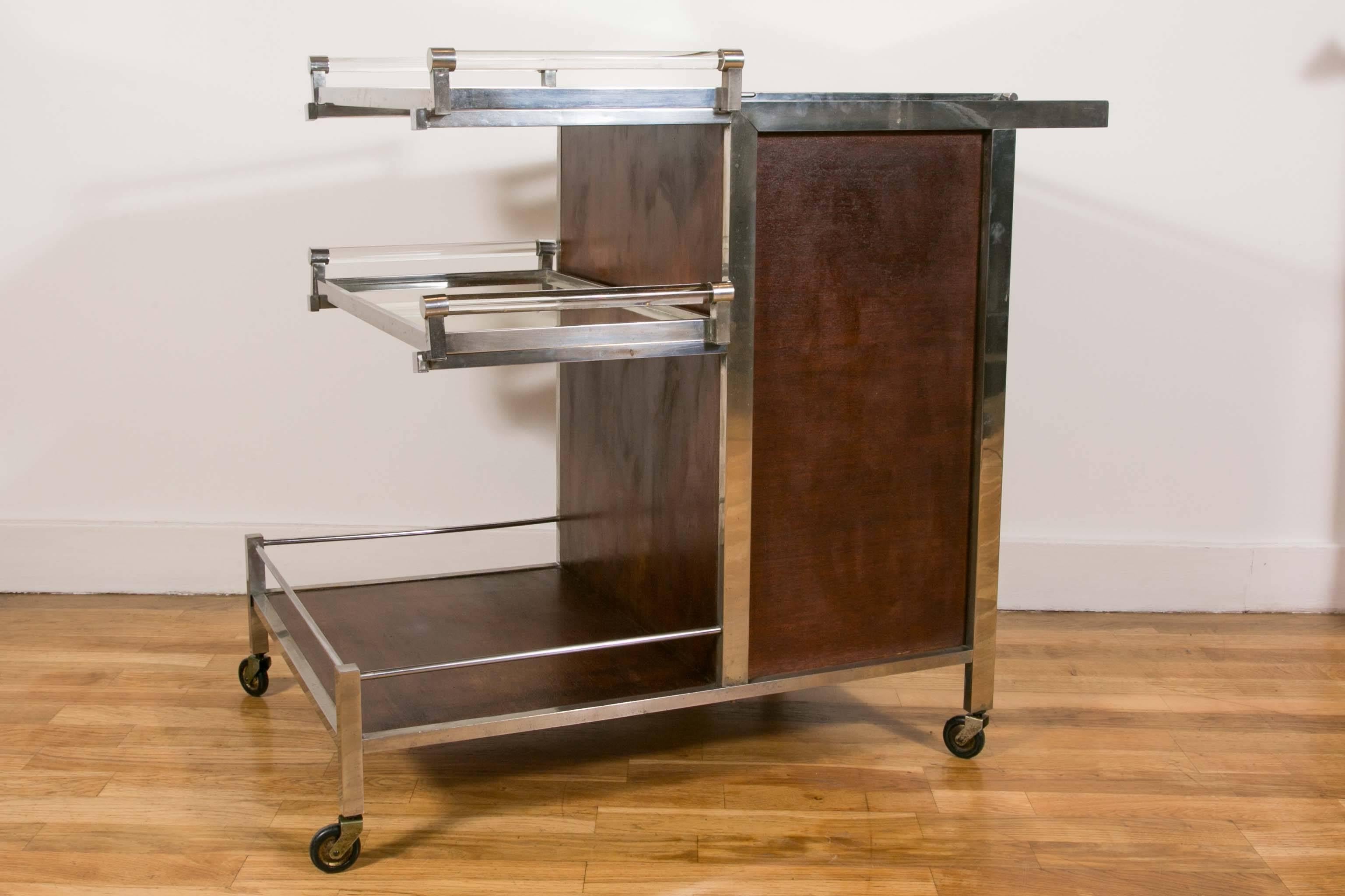 Bar cart/dry bar by Jacques Adnet (1900-1984). Mahogany, nickel-plated metal, mirrors and glass. Two removable trays, one top compartment, one compartment with two doors for bottles and glasses with glass holders. Tray handles and pushbar in solid