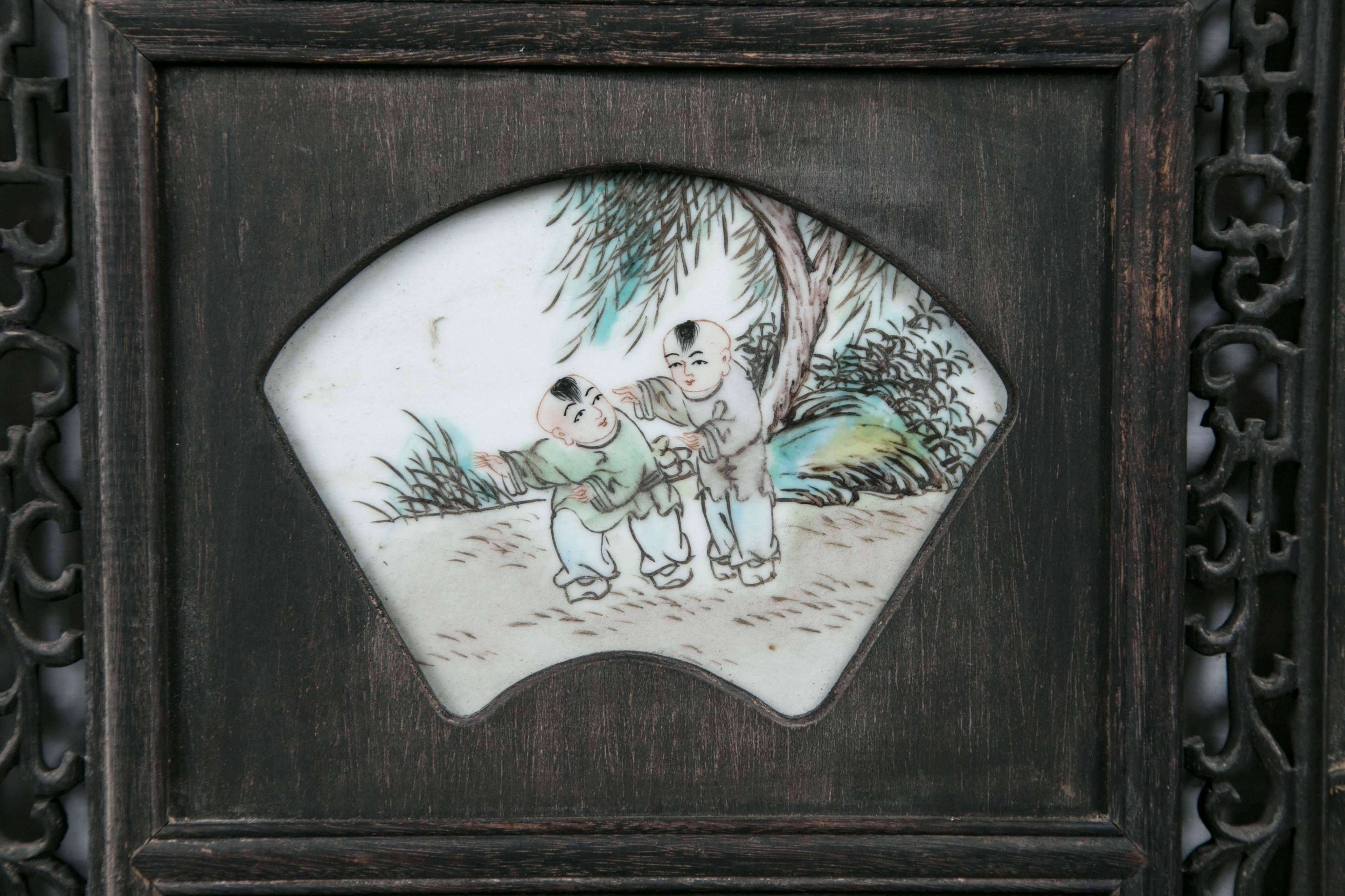 Set into a hardwood panel with open fret work and carvings. Hand-painted porcelains plaques of:
From the top: Boys at play, a beggar, a man and boy with a toy (?)

              