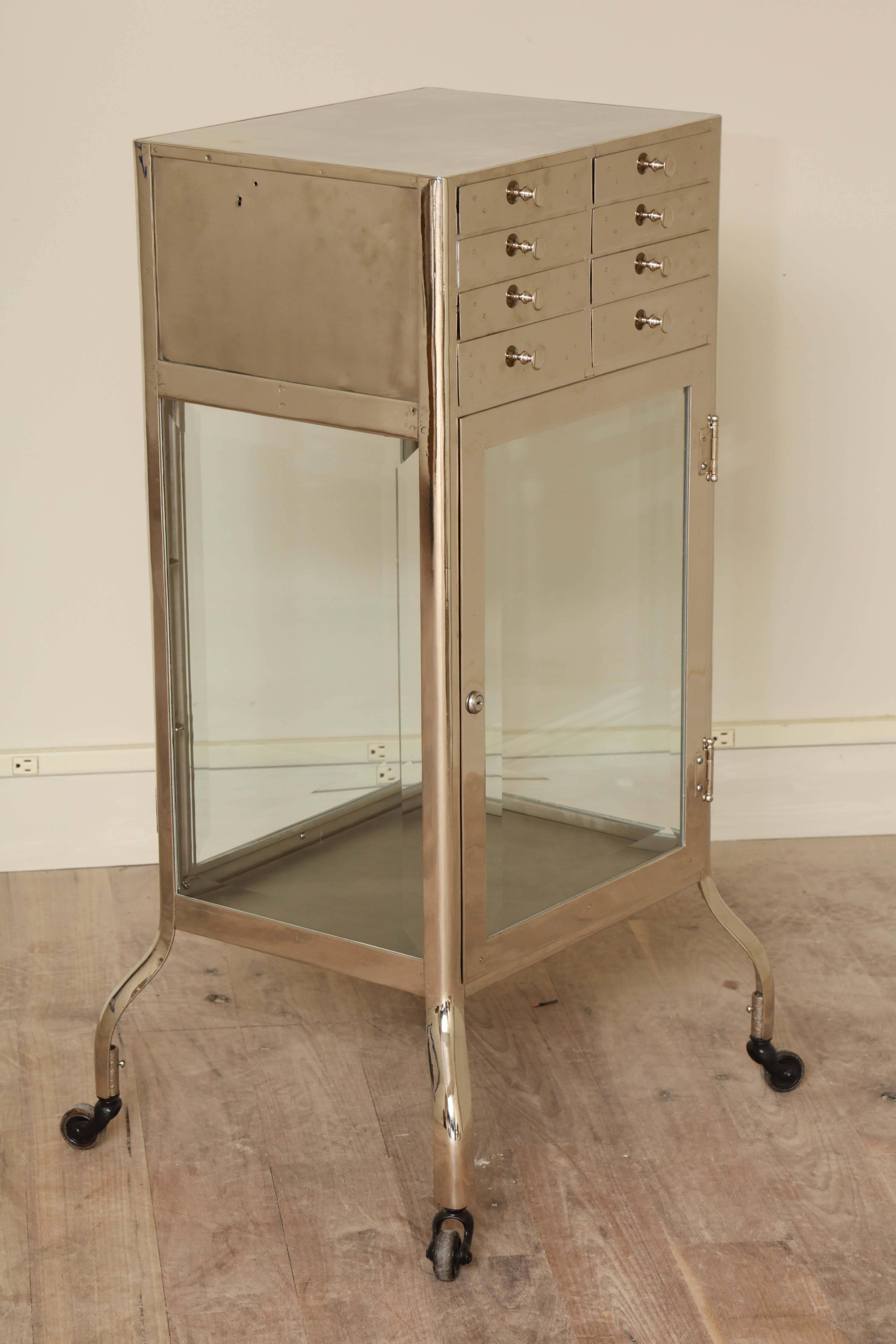 Chrome-plated Industrial cabinet with a bank of eight drawers over a double-sided locking cabinet with beveled glass shelves and doors, circa 1940.