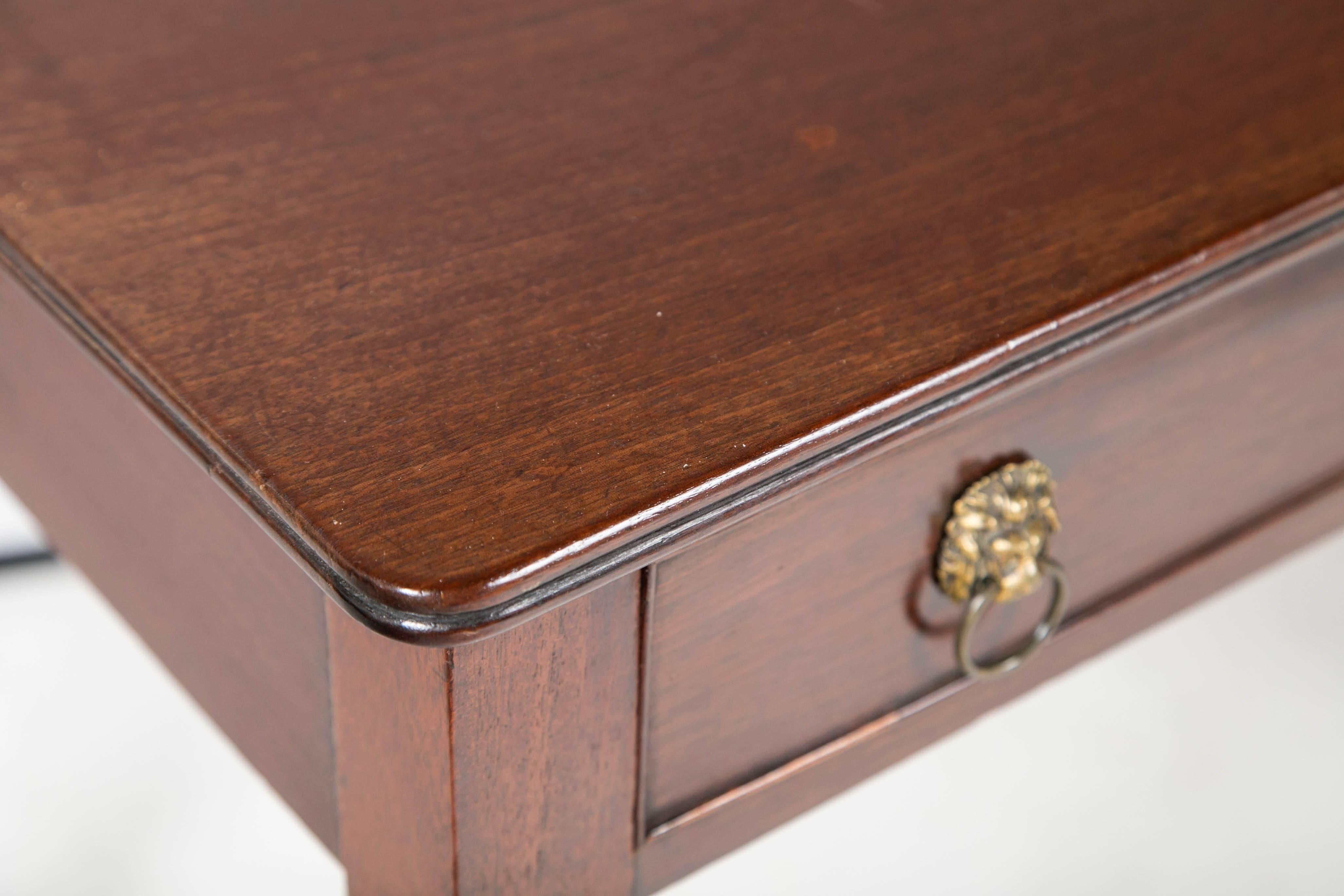 English late 19th century mahogany writing table with elegantly turned legs and novel brasses.