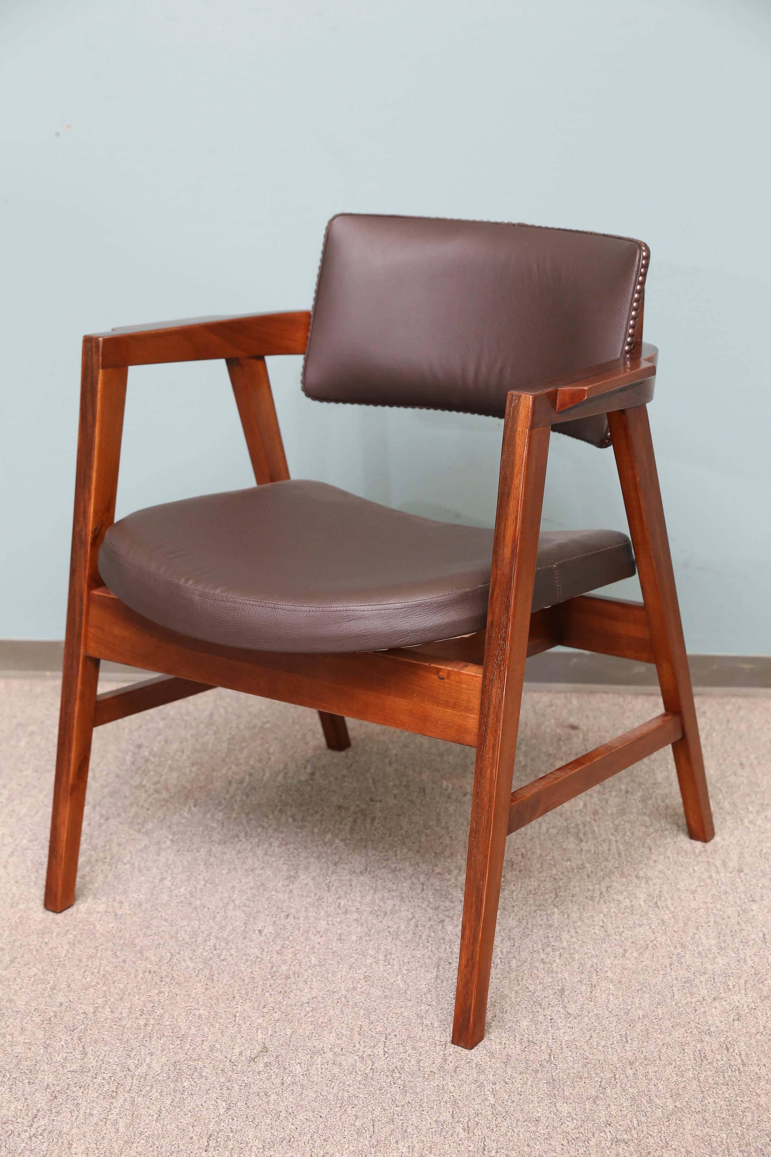 Very fine chair, sit and back are covered with cowhide. The base of the chair build out of high quality walnut wood. The chair has armrests. Top and sides of the back of the chair embellished with round decorative nails. The label attached on the