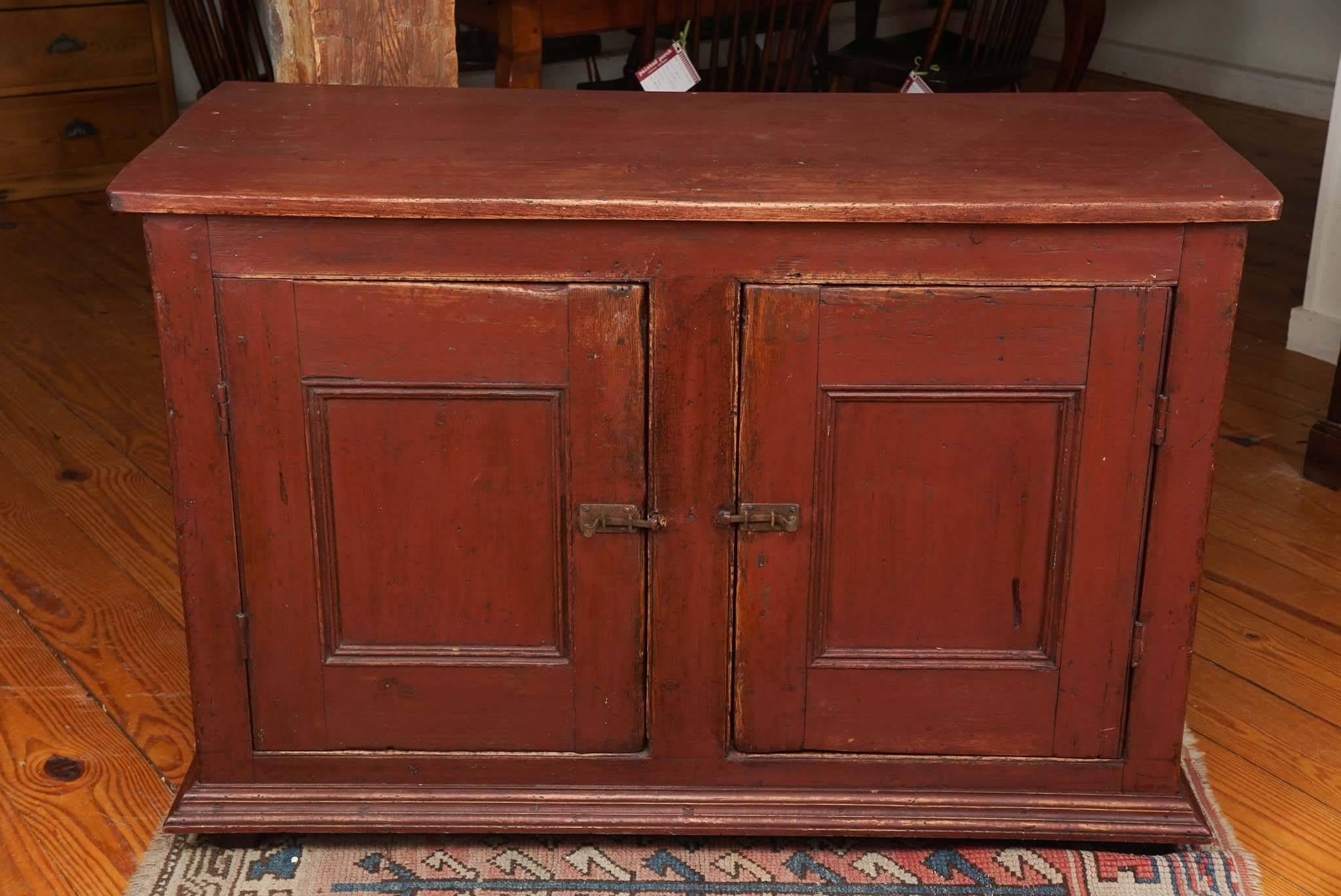 This is a very warm color red Quebec buffet and very old, about circa 1830 with its original hardware and original shelf inside. The French Canadians loved painted furniture and this color is perfect.