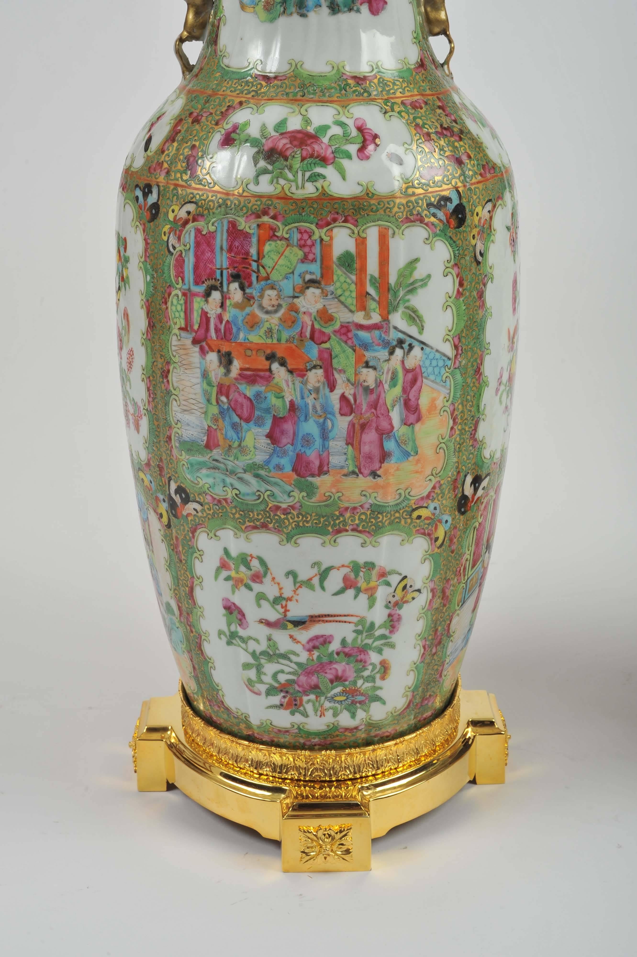 This lovely pair of Canton vases that were converted to lamps feature ornate ormolu mounts to the top and the base, and are hand-painted with a detailed design of family figures in an garden setting with various bird and floral motifs against a
