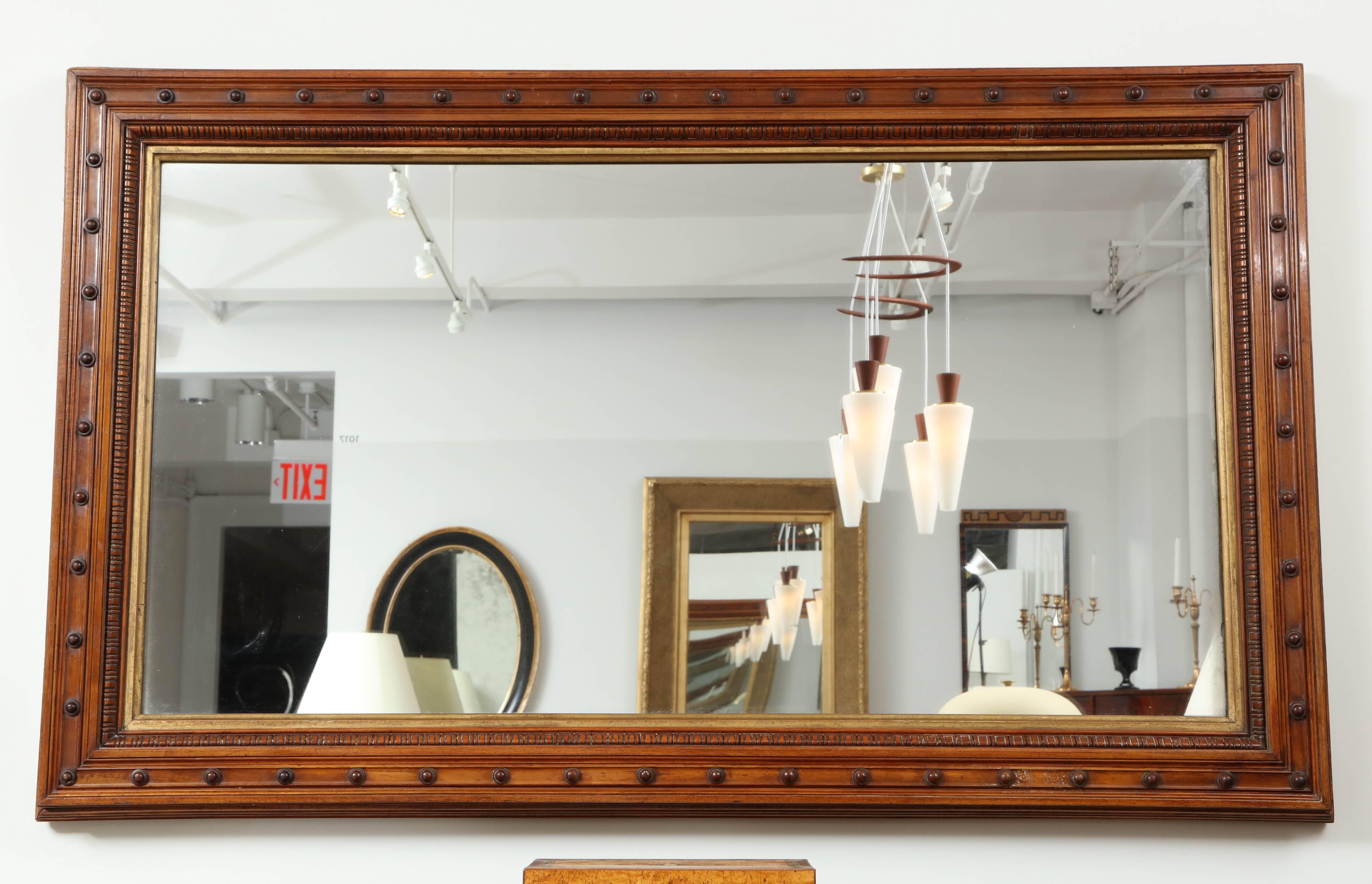 A large Danish walnut and parcel-gilt mirror, circa 1900, the original mirror plate surrounded by a gilded inner frame, carved walnut beaded edge and wide section molded frame mounted with carved roundels.

Good color, original glass and gilding.