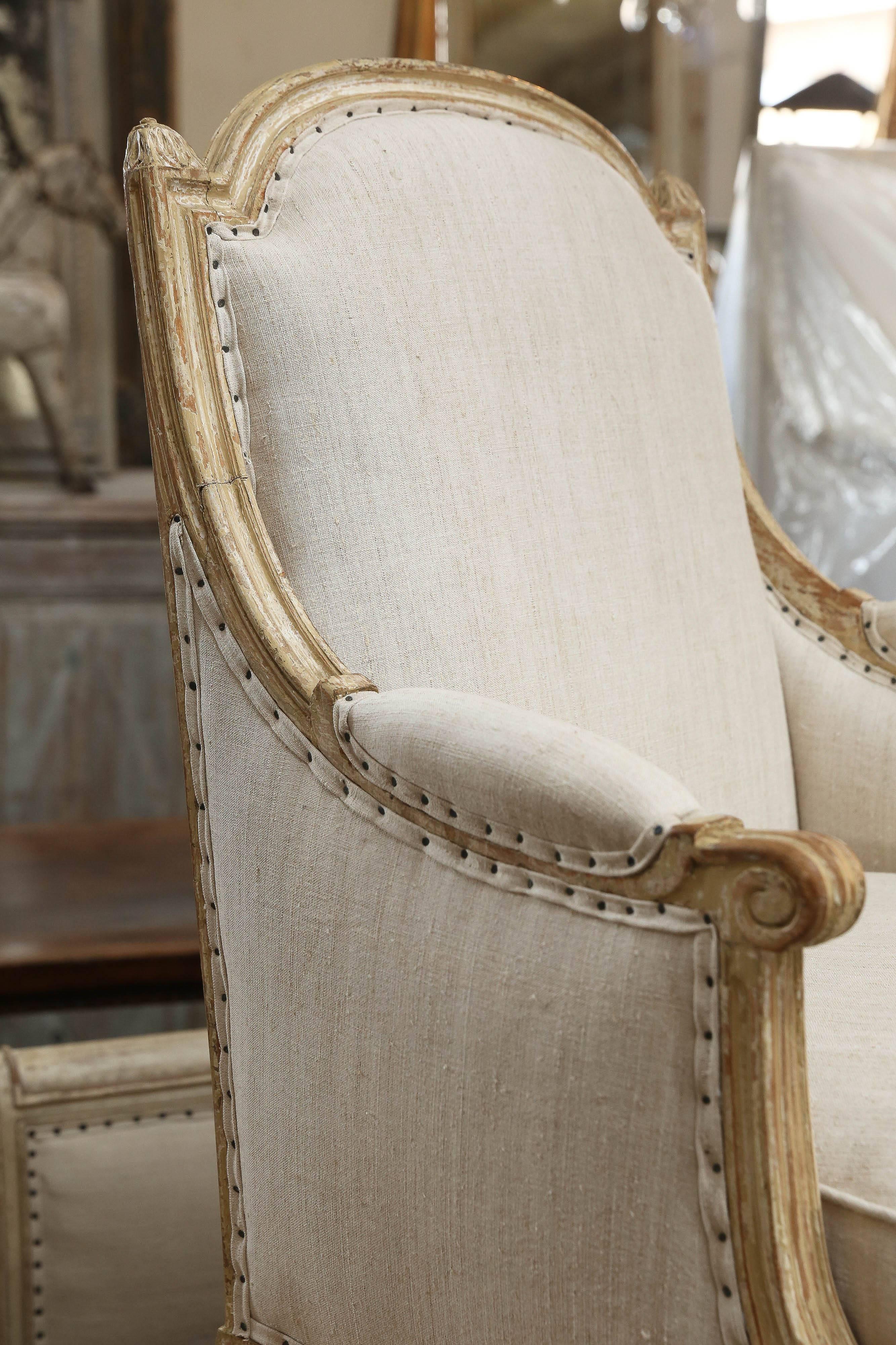 Fauteuils bergères français avec peinture crème d'origine, vers 1850. Ces chaises sont de grande taille et s'intègrent dans n'importe quel cadre moderne ou traditionnel. Ils ont été nouvellement tapissés en lin hongrois vingage et les coussins sont