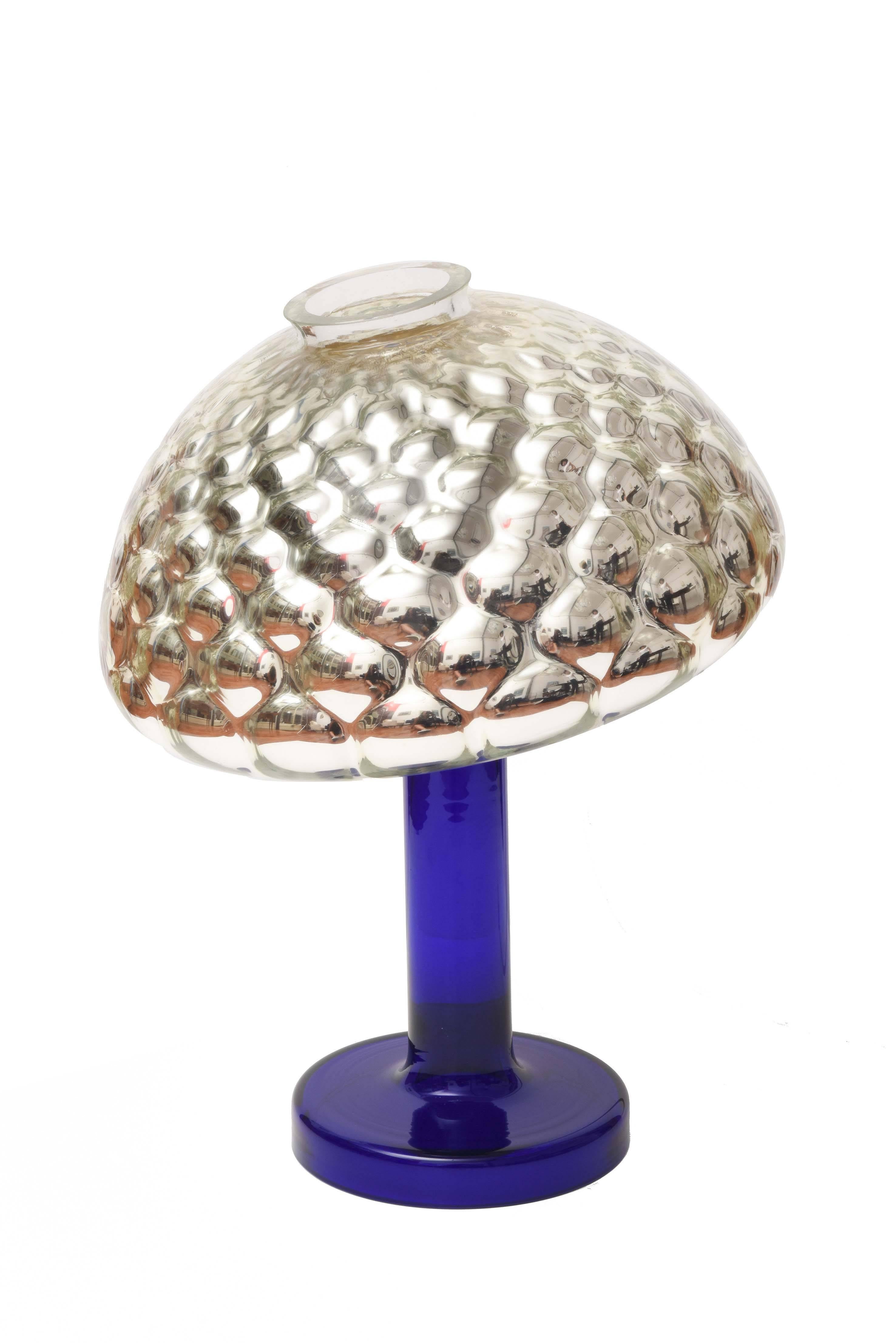 Table halogen lamp. Base and stem in cobalt blue glass in a single piece. Adjustable diffuser in silver optical glass honeycomb leaning against the base and removable. Electrical equipment resting on the bottom of the lampshade magnetically and