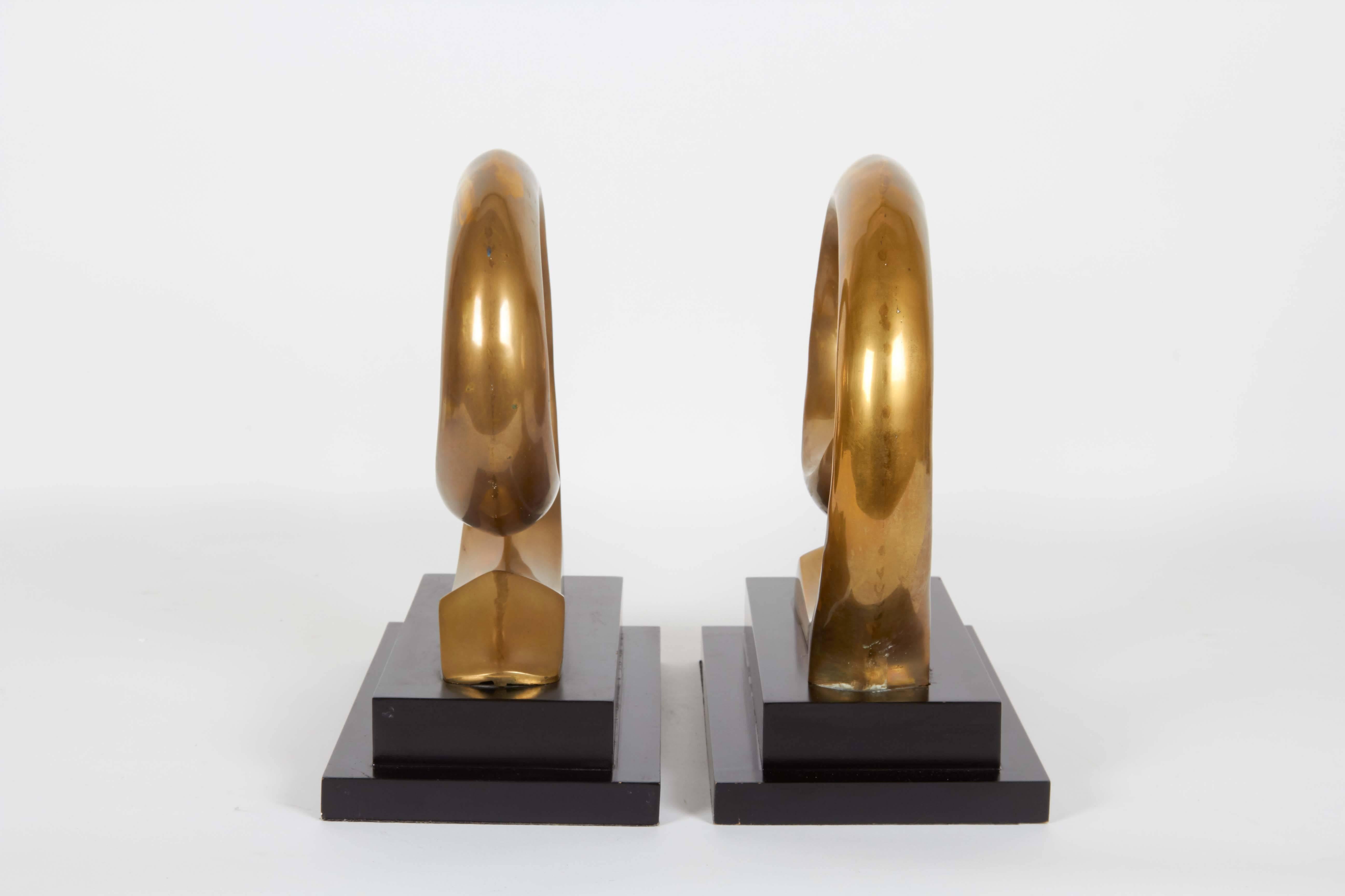 Very rare Pierre Cardin logo bookends, produced circa 1970s with swirling bodies in brass on stepped black bases. The bookends remain in good vintage condition with wonderful patina, wear consistent with age and use.