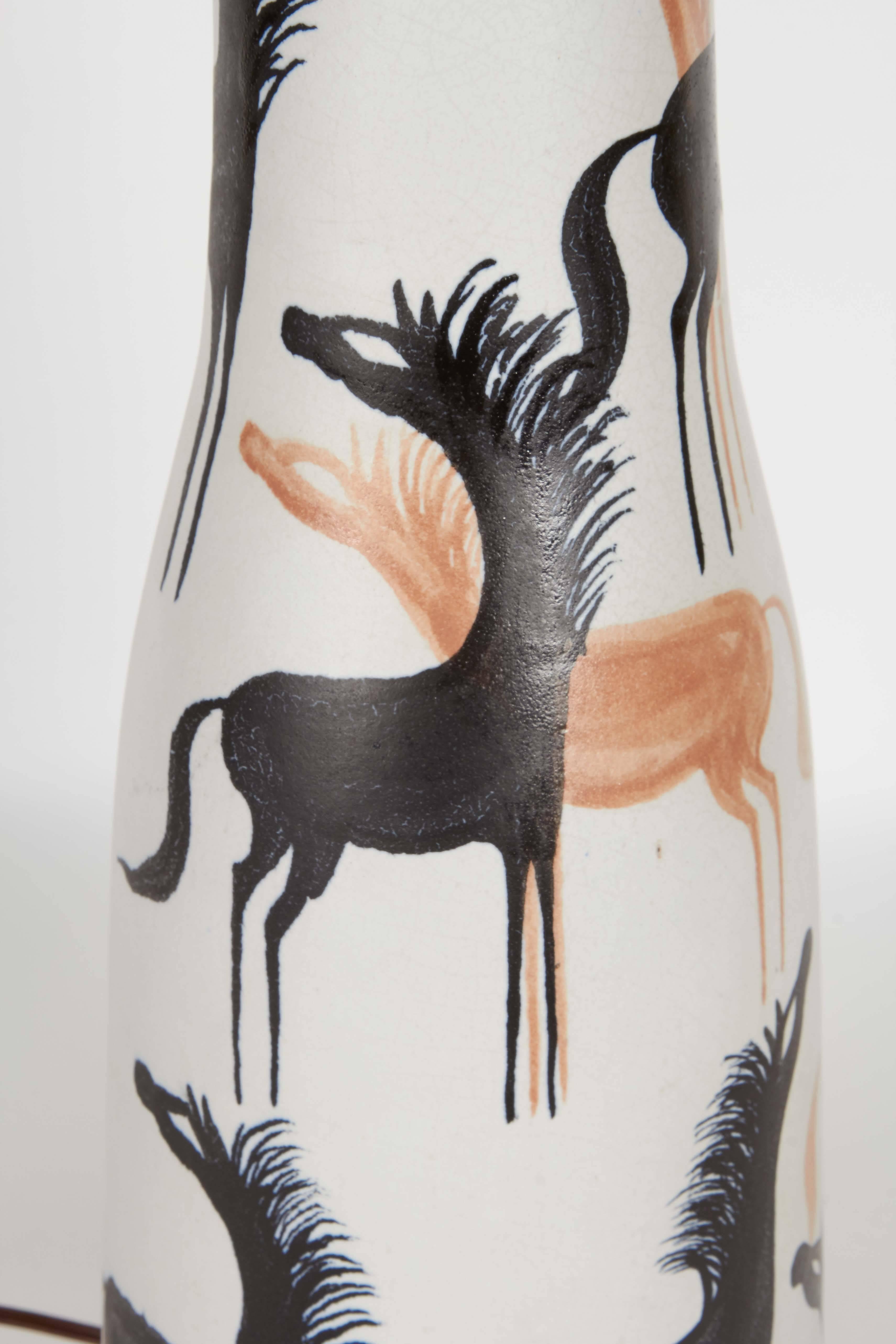 A ceramic lamp circa 1960s, manufactured in Italy, the single socket on a tapered body with matte glaze, decorated with orange and black horses in the primitive style. This lamp remains in very good vintage condition, wear consistent with age and