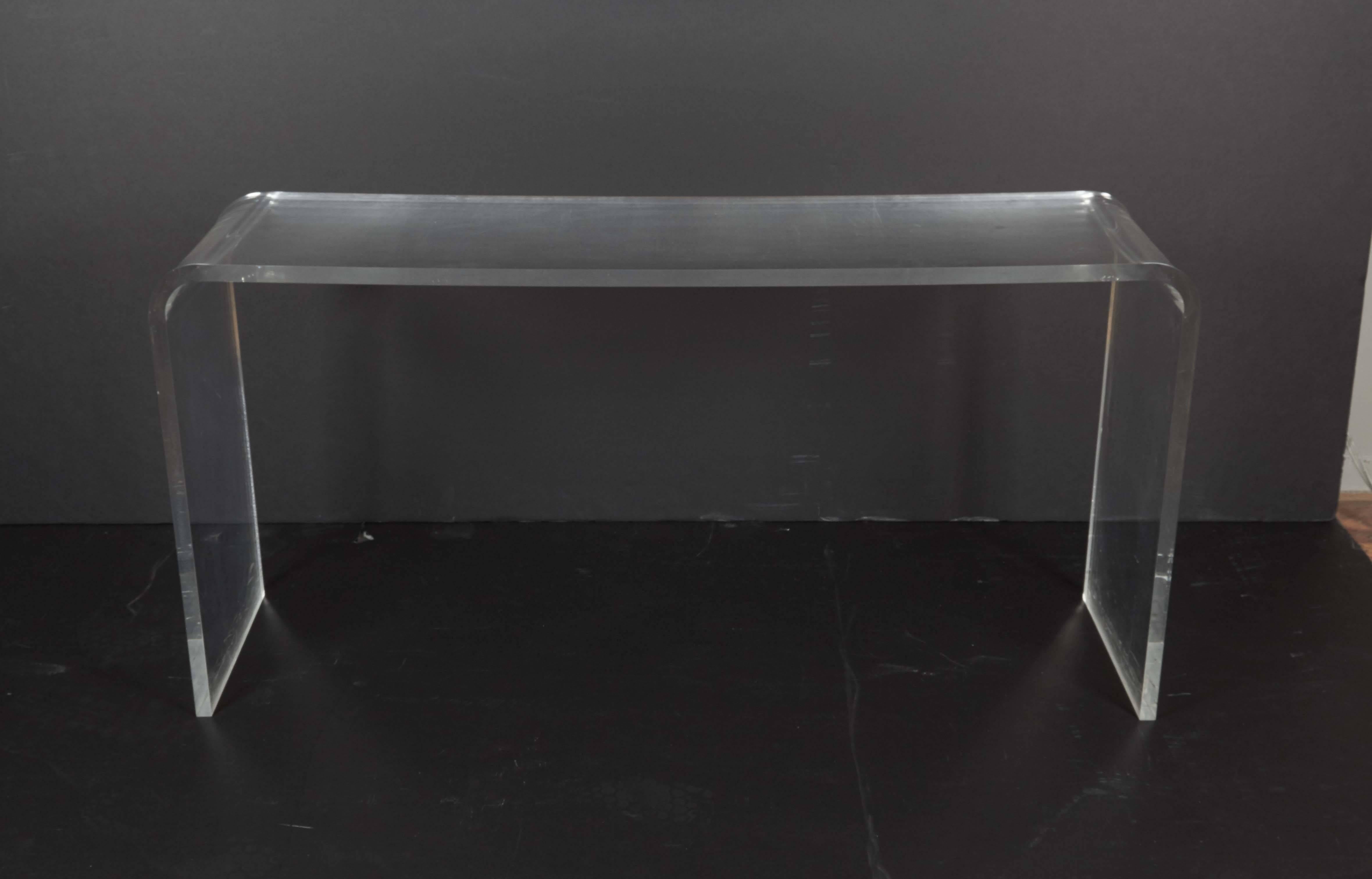 A modernist waterfall console table, entirely in Lucite, circa 1970s. This console remains in good overall condition, any presence of wear consistent with age and use.

10361