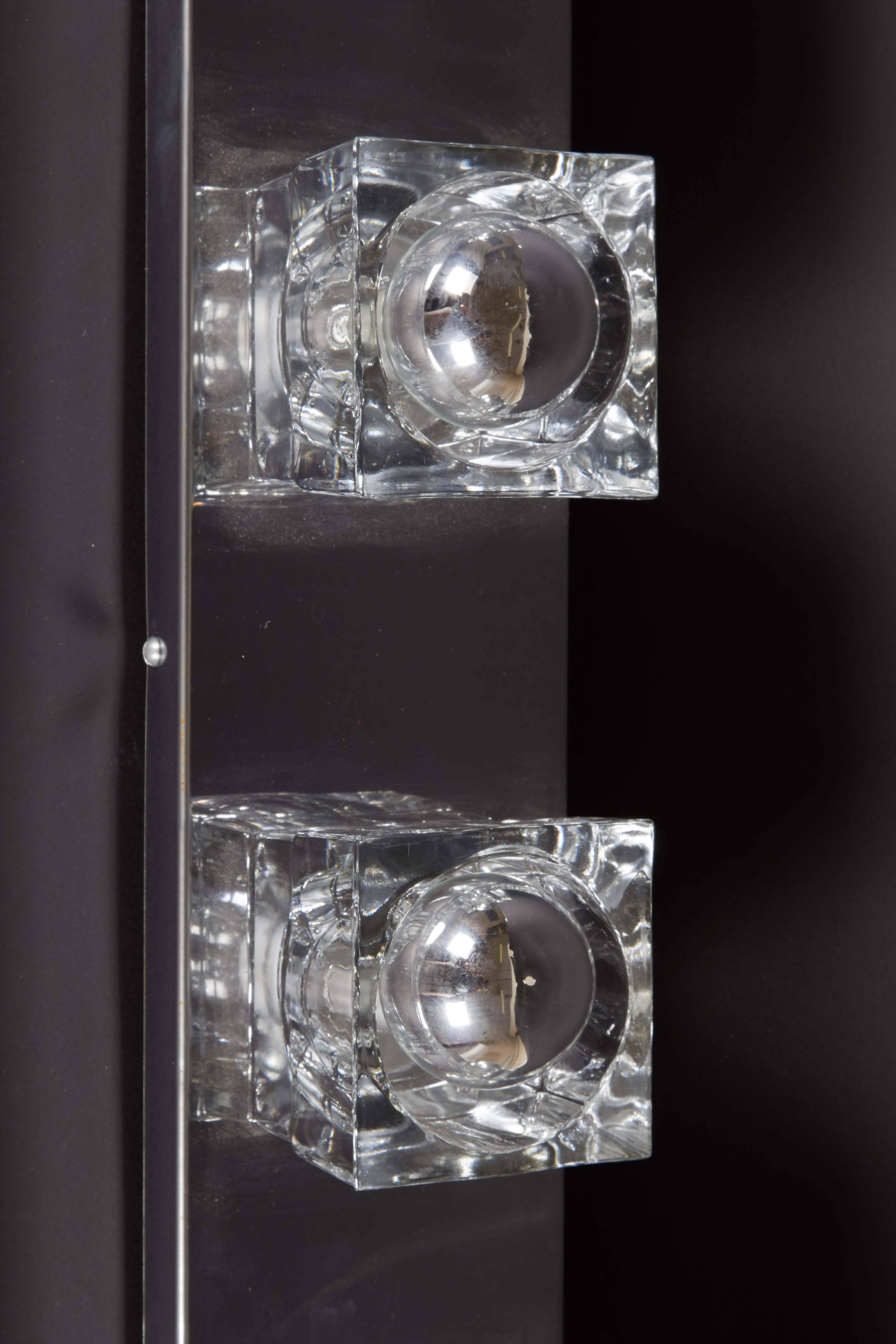 A modernist wall light fixture by Peill and Putzler of Germany, manufactured circa 1970s, with six cut-glass block socket covers, mounted to a rectangular polished chrome backplate. Sockets to US standard, requires E12 bulbs. This light fixture