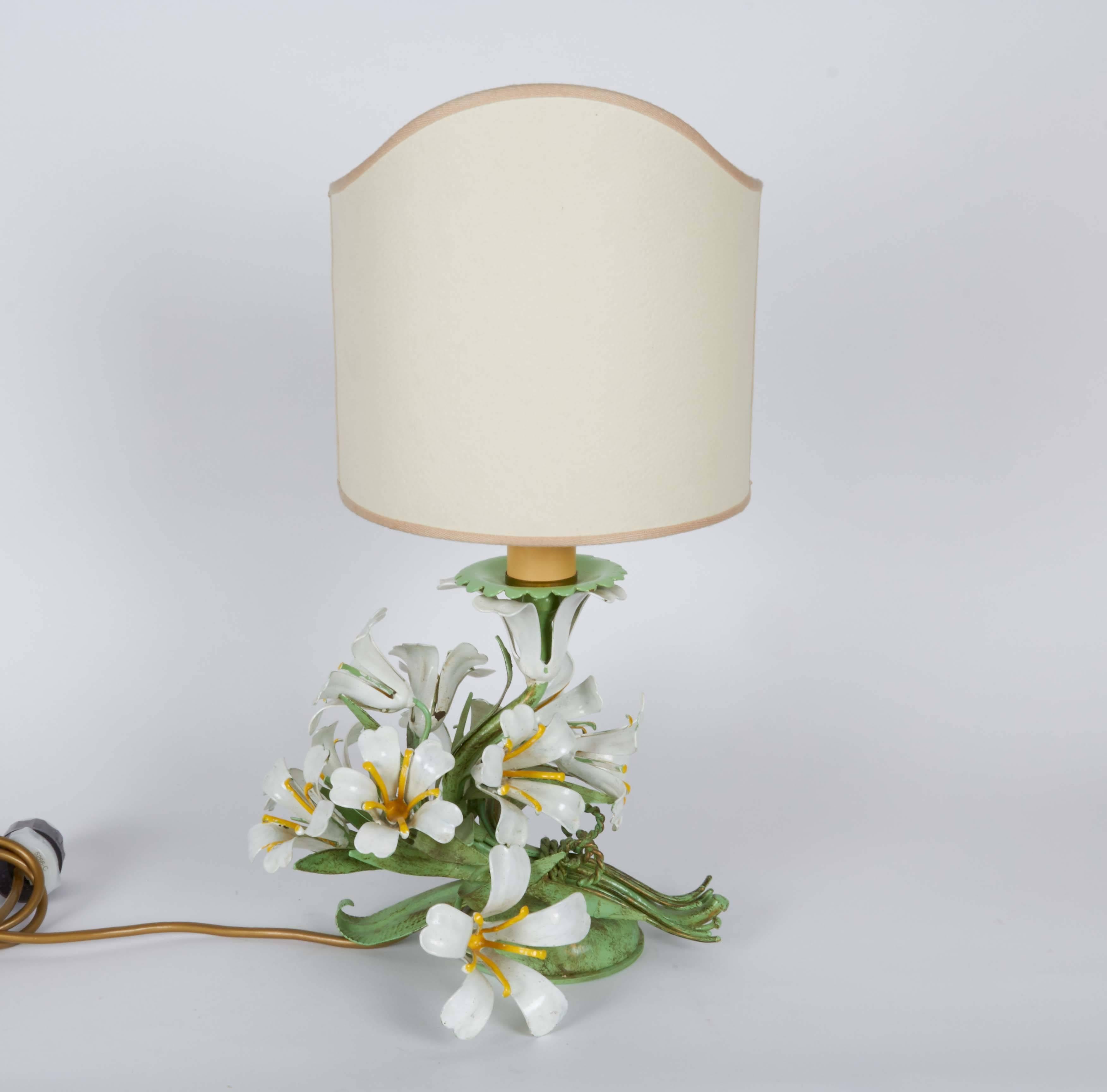 A pair of circa 1940s floral lamps in enameled metal, manufactured in Italy, each with their original curved shades, single sockets on bodies comprised of curling leaves and flowers. The lamps remain in overall good vintage condition, minor wear