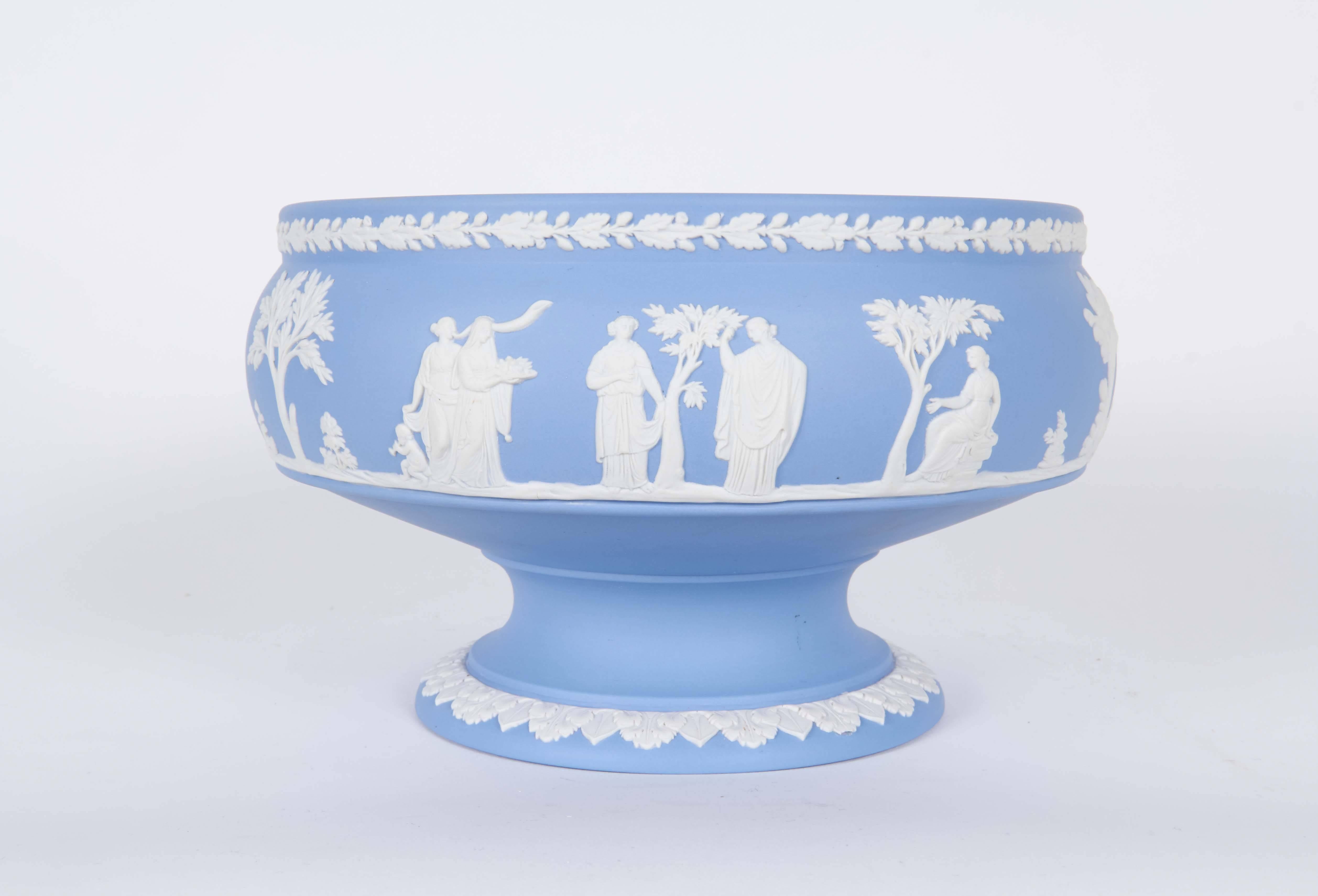 A pair of porcelain candlesticks and matching bowl manufactured by Wedgwood circa 1950s, each in brilliant blue jasperware, depicting classical Greco-Roman scenes in relief. Markings include [Made in England] and [Wedgwood] impressed to the bases of