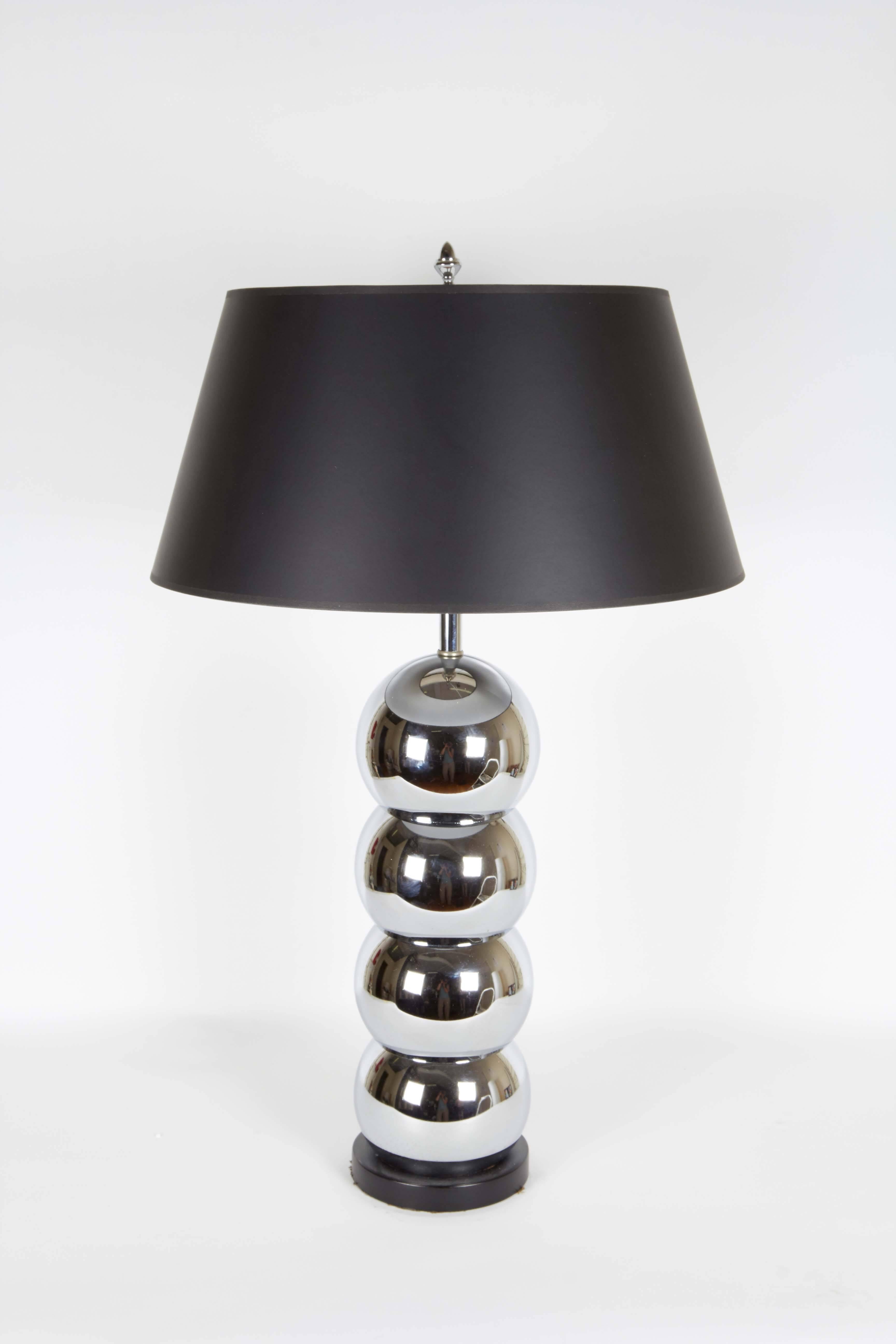 A pair of modernist table lamps by George Kovacs, manufactured in the United States, circa 1960s, with single socket and stem above bodies comprised of mercury glass, formed into four stacked balls, mounted on metal bases in black enamel. Wiring and
