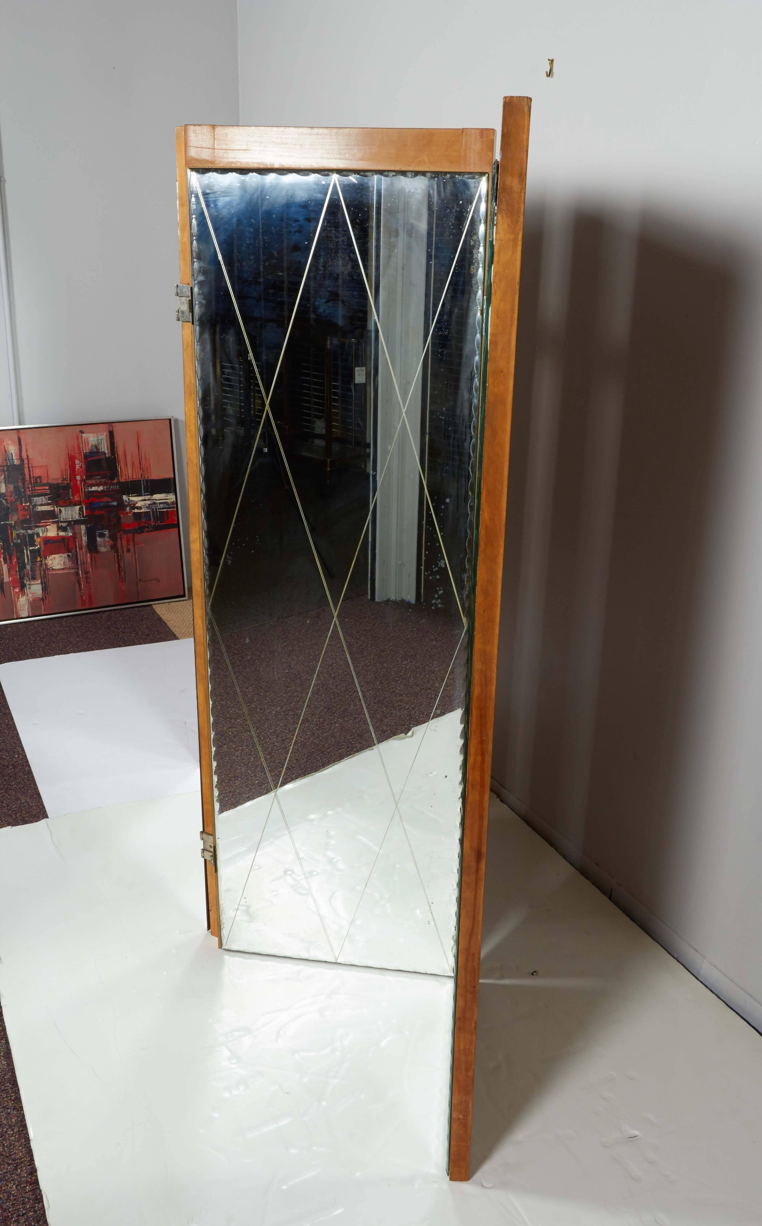 A screen and room divider in the Hollywood Regency manner, manufactured, circa 1940s to 1950s, with four wood base panels with mirrors, diamond forms etched to glass surface, bordered by beveled patterns. Good overall vintage condition with age