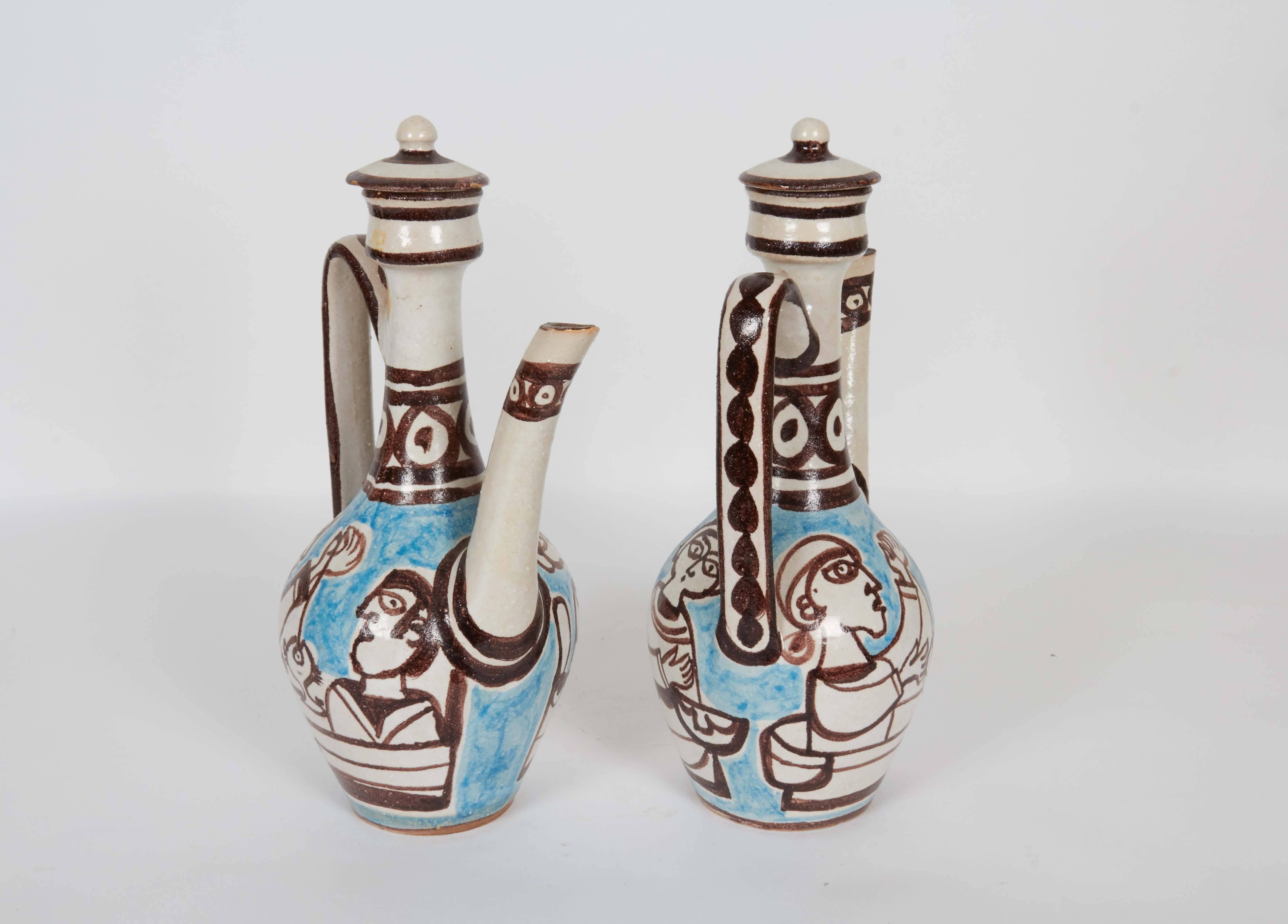 A pair of lidded pottery ewers by ceramic designer Giovanni de Simone, produced in Italy, circa 1960s, each with handle and long spout, decorated with brown, white and blue glazes. Markings include [DeSimone/ ITALY/ 37] to the underside of the